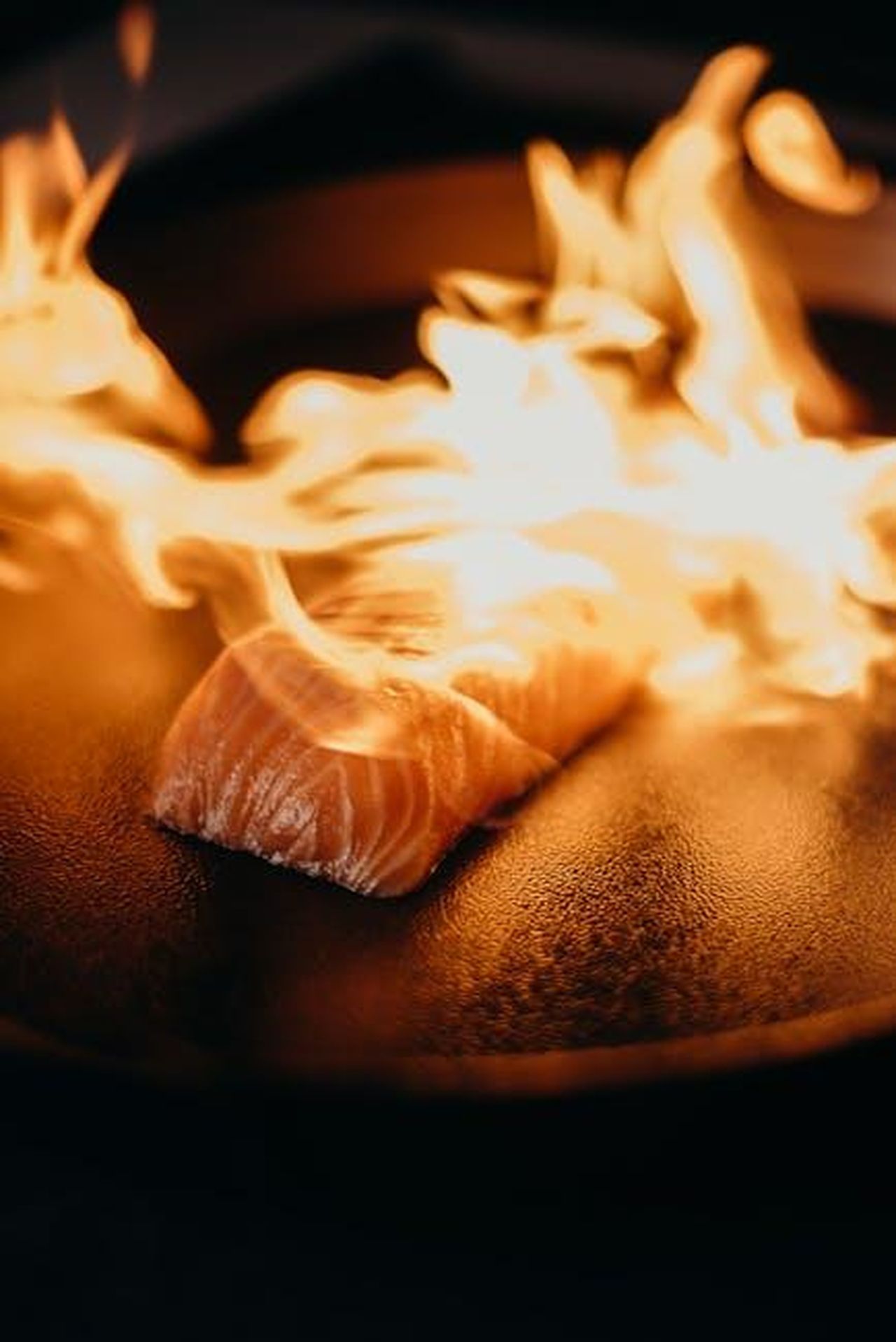 Dove_acquistare_lolio_di_salmone_Tw93g9YxZV - Confidenze24 Source: cottonbro studio - pexels - Close-up of a salmon fillet being seared with flames on a black iron pan, highlighting culinary artistry.