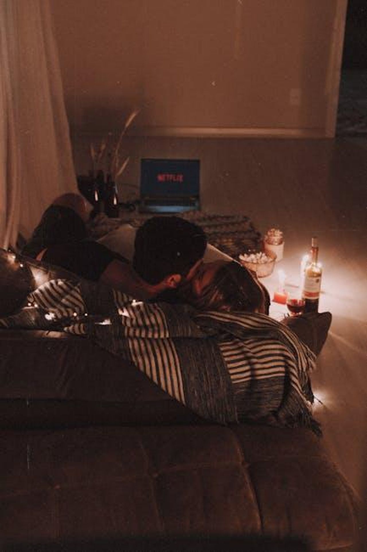 Dove_posso_vedere_il_primo_Moana_PS8c5BKS3d - Confidenze24 Source: Edward Eyer - pexels - Cozy indoor movie night setup with a couple cuddling on a couch, surrounded by candles and wine.