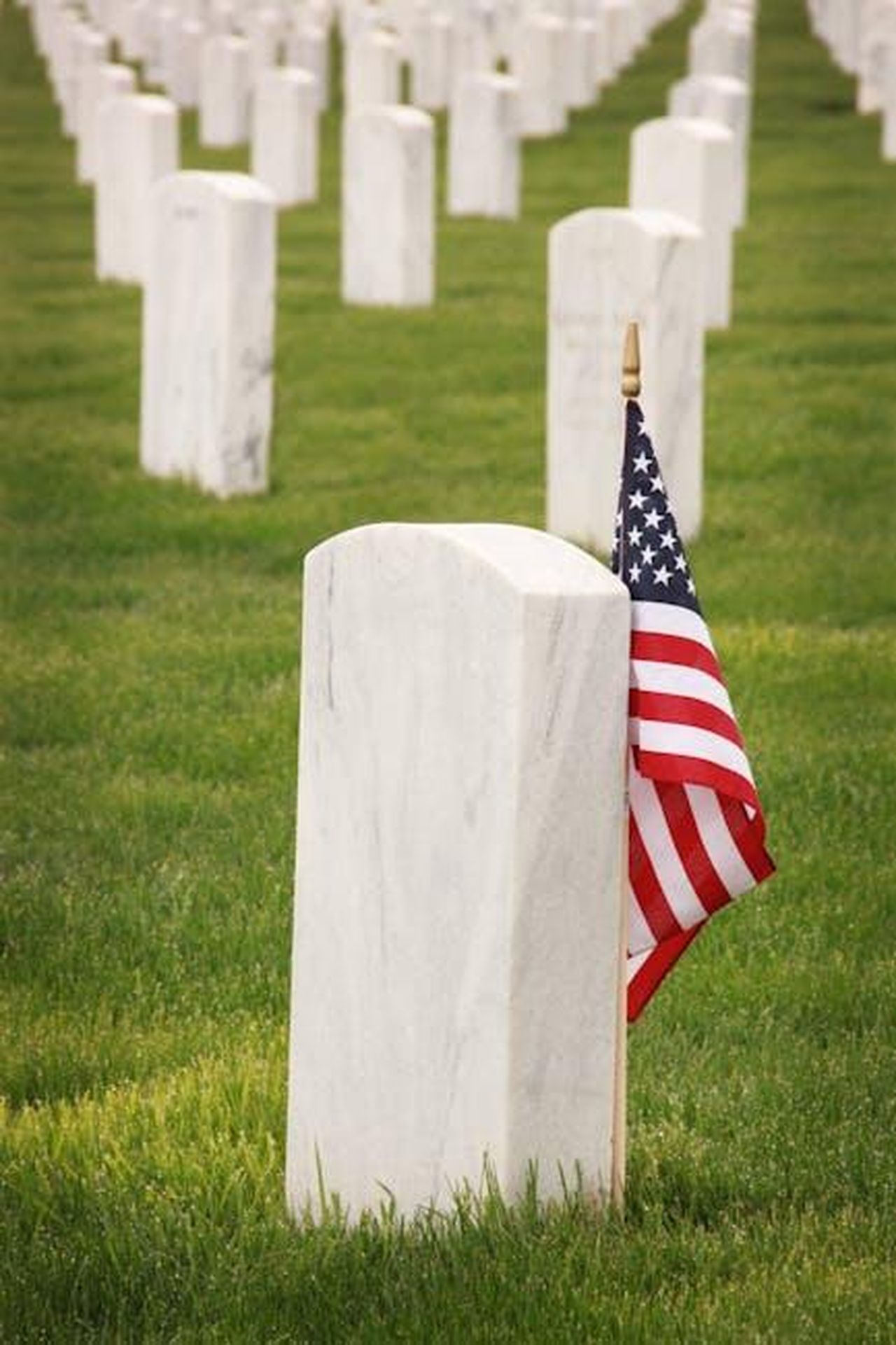 Era_un_personaggio_che_nessuno_dimenticher_mai_mCRta5JBks - Confidenze24 Source: Sharefaith - pexels - Rows of gravestones with an American flag, honoring fallen soldiers.