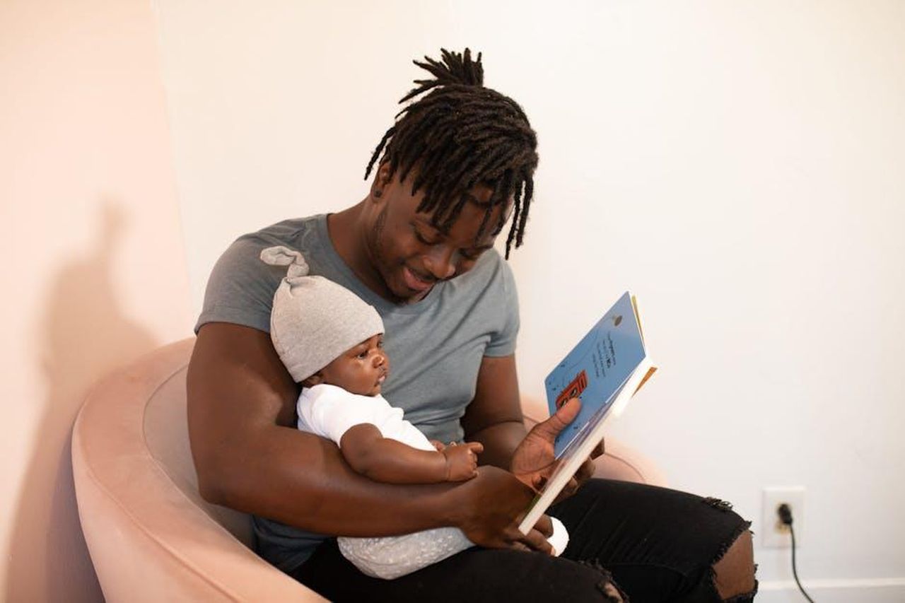 Essere_genitori_kMxwwHMAj1 - Confidenze24 Source: nappy - pexels - A loving father reads a book to his baby, fostering an affectionate bond.