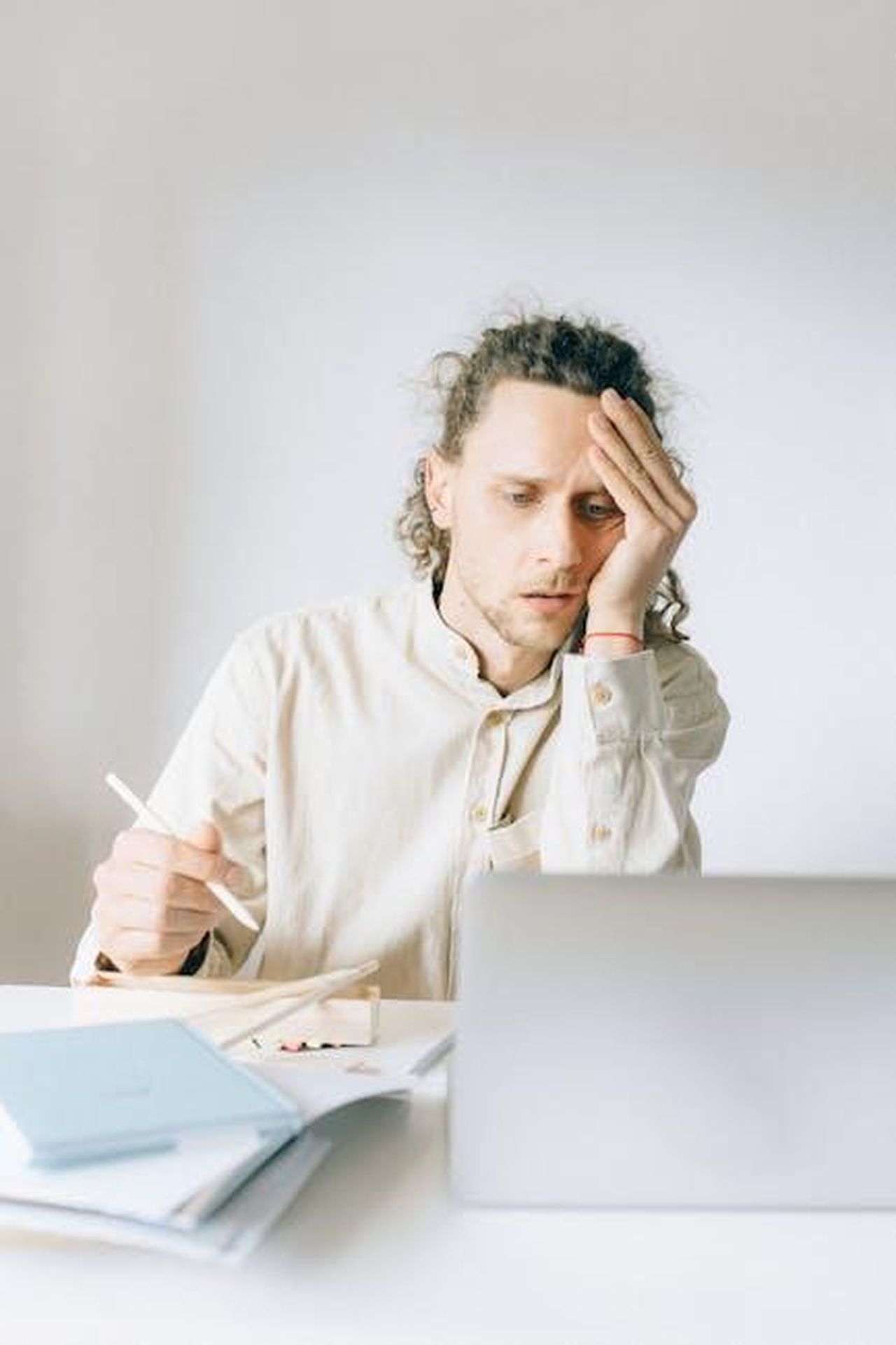 Faye_Marsay_e_la_sindrome_dellimpostore_HbT3id5nie - Confidenze24 Source: Nataliya Vaitkevich - pexels - Young man overwhelmed by work at his desk, showing stress and fatigue.