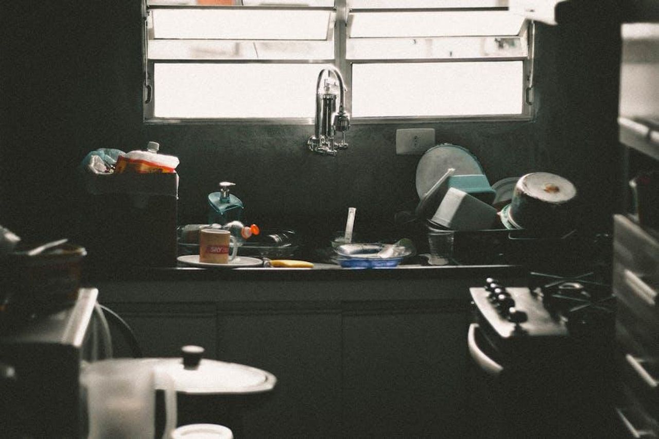 Finirai_costantemente_senza_piatti_puliti_Au7PGoTgii - Confidenze24 Source: Wallace Chuck - pexels - A cluttered kitchen sink filled with dirty dishes and utensils near a window, creating a messy home interior scene.