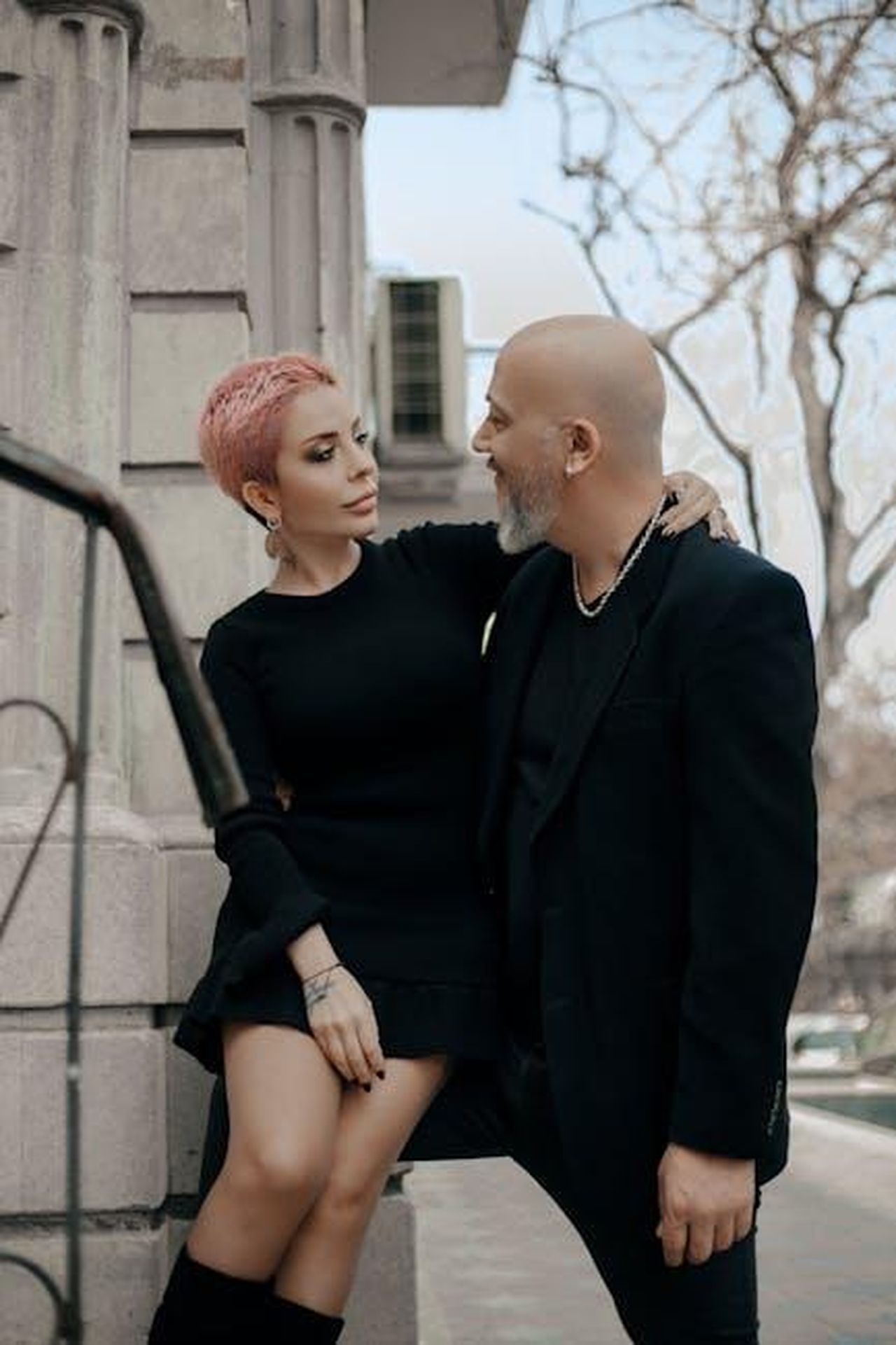 Gemelli_21_maggio__21_giugno_eStErXzD0X - Confidenze24 Source: Eko Agalarov - pexels - Elegant short haired woman in black dress embracing stylish bald middle aged man while standing together near old stone building in city