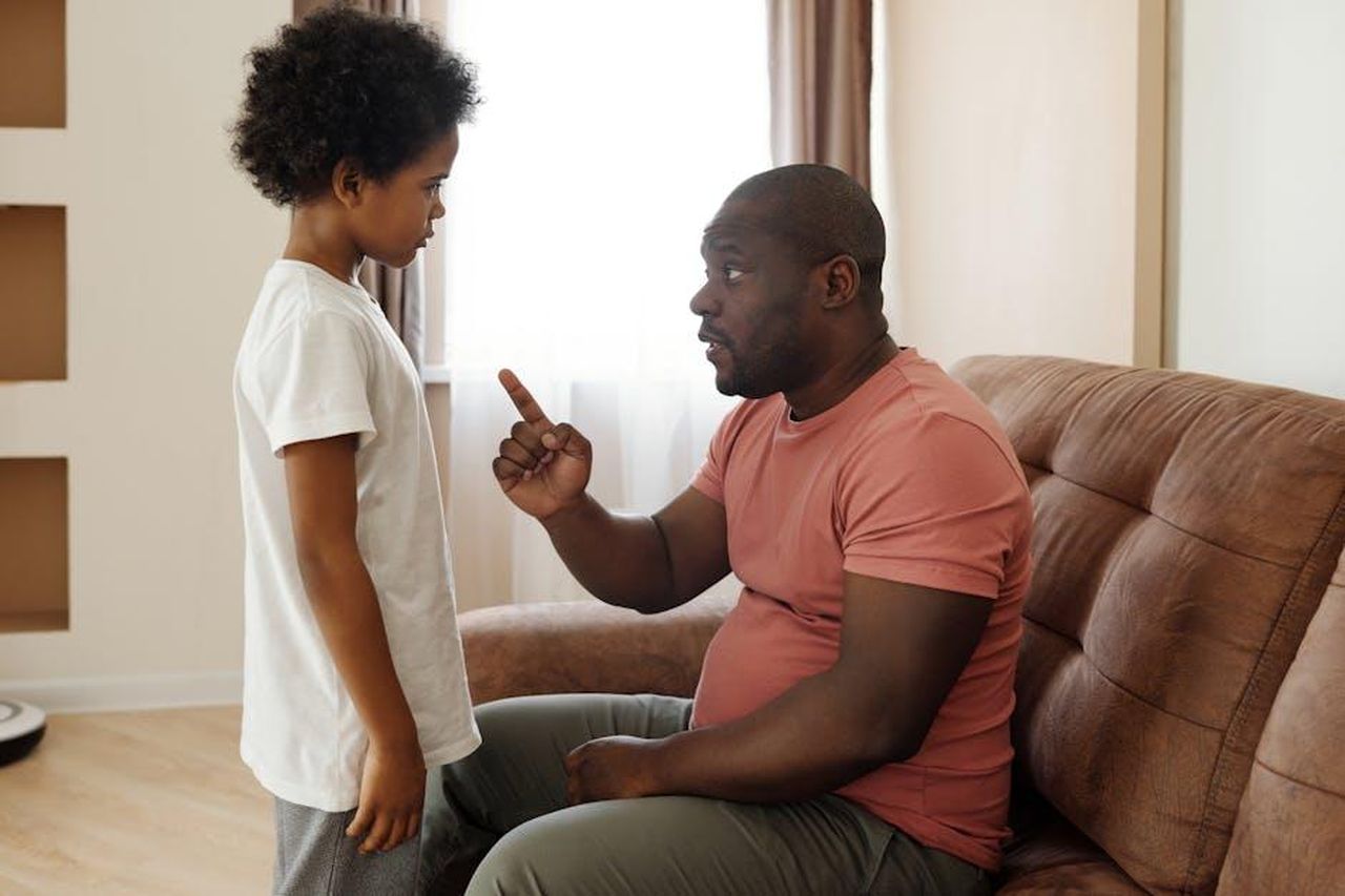 Genitori_protettivi_lKzHtu3S6u - Confidenze24 Source: August de Richelieu - pexels - Father and son engaged in a heartfelt conversation on the sofa, illustrating parenting in a loving family setting.