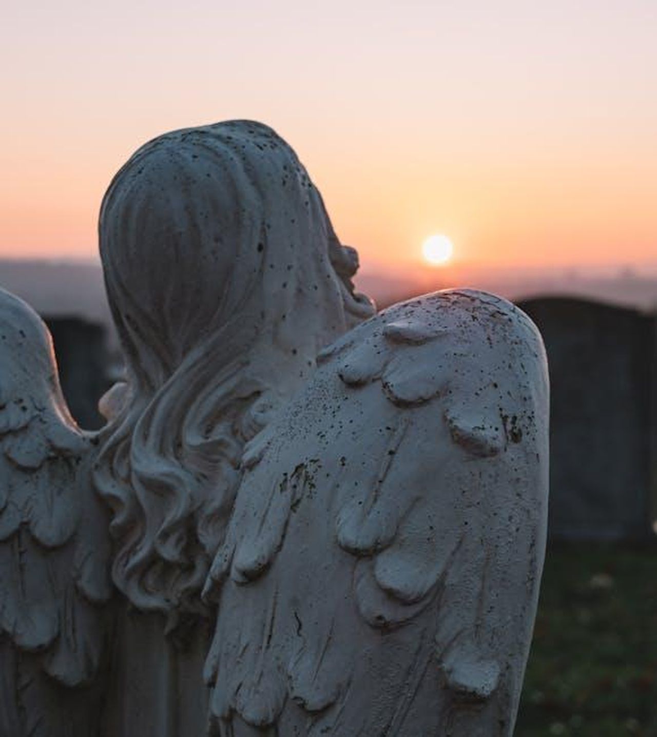 Gennaio_2025__La_morte_straziante_di_Linda_3GZglH4E7W - Confidenze24 Source: Ellie Burgin - pexels - A contemplative angel statue in a cemetery, facing a serene sunset sky.