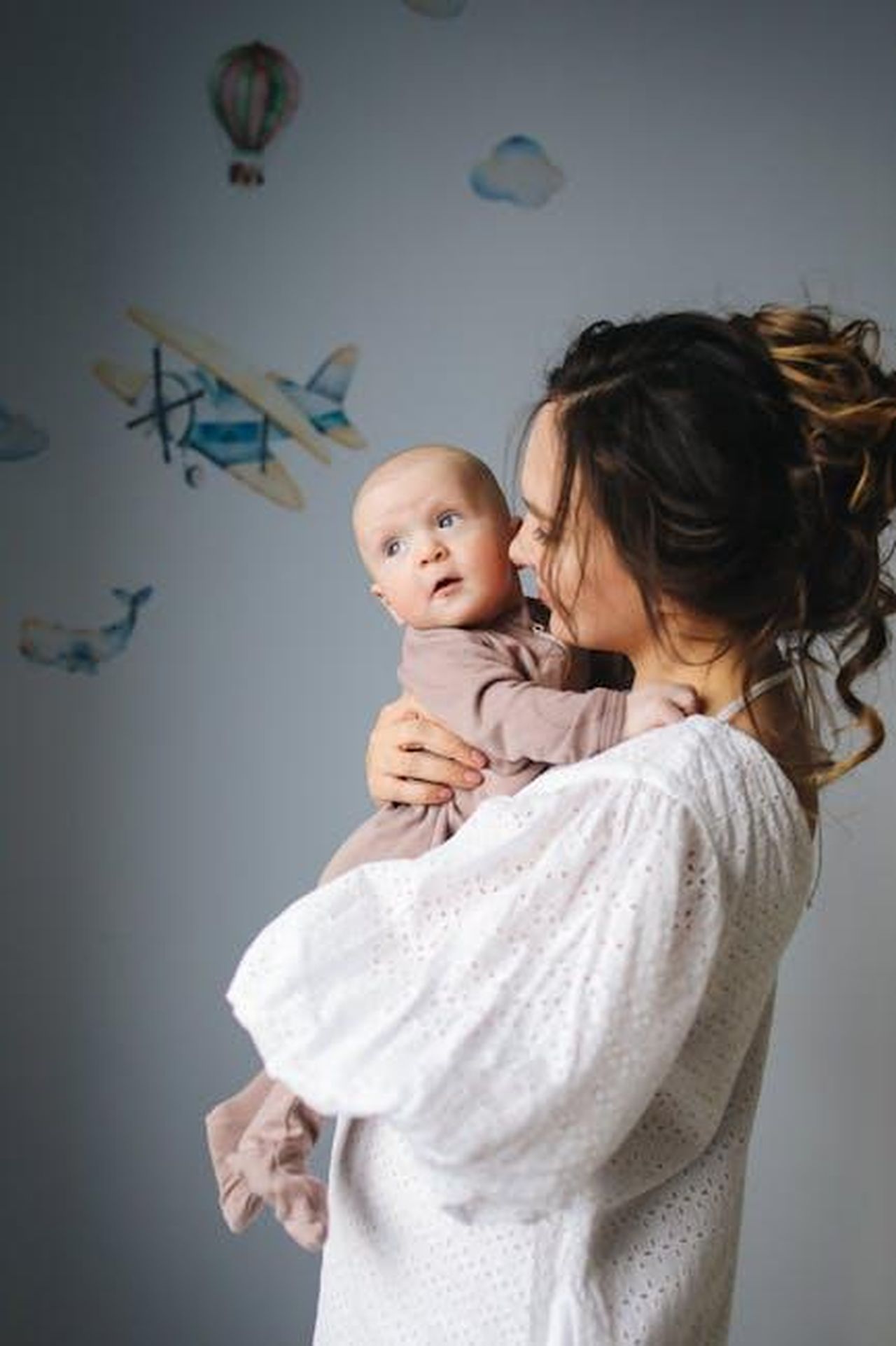 Georgia_May_Jagger_e_la_maternit_rDkAqlMTfq - Confidenze24 Source: Polina Tankilevitch - pexels - A mother lovingly holds her baby in a nursery decorated with airplanes.