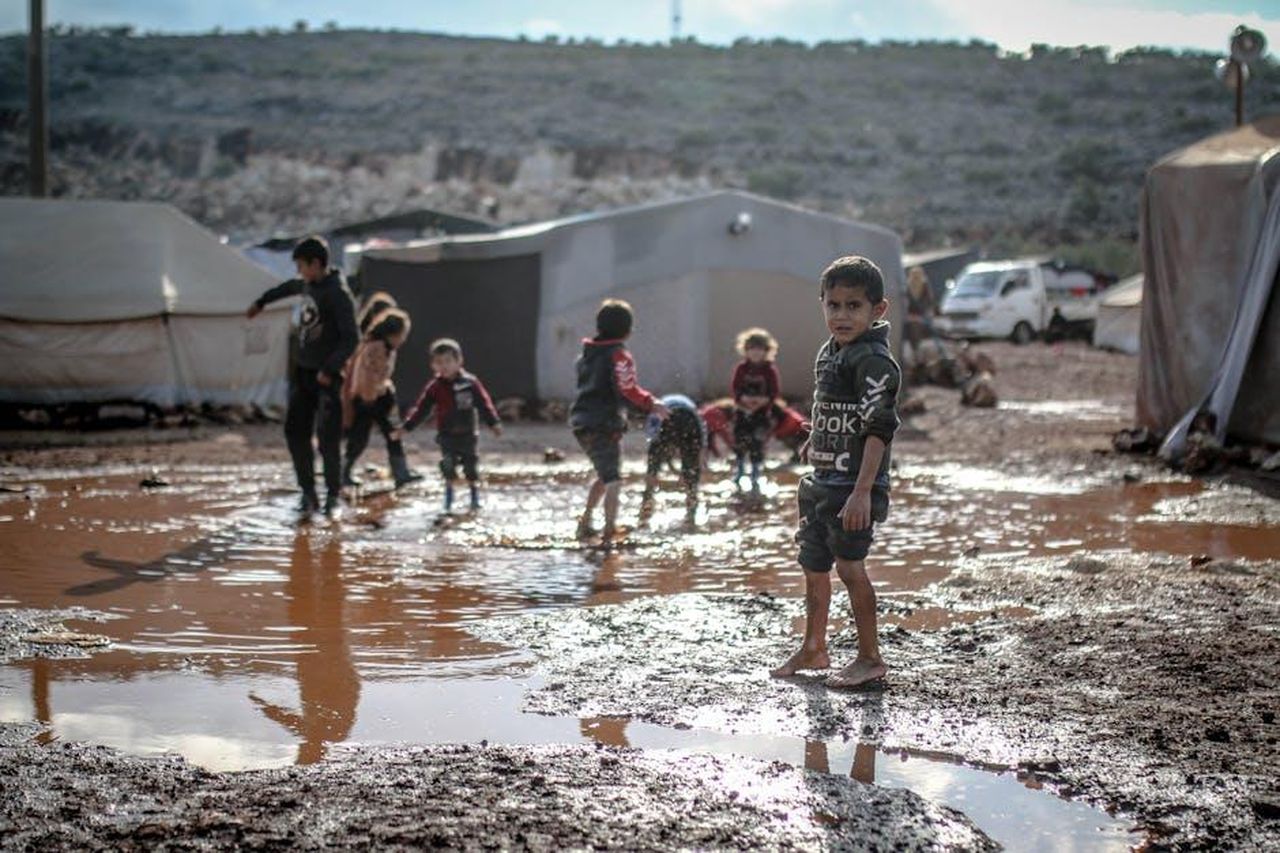 Georgia_si_trasferisce_dopo_lo_scandalo_9AkpBBPDZ0 - Confidenze24 Source: Ahmed akacha - pexels - Children enjoy playing in muddy puddles at a refugee camp in Idlib, Syria.