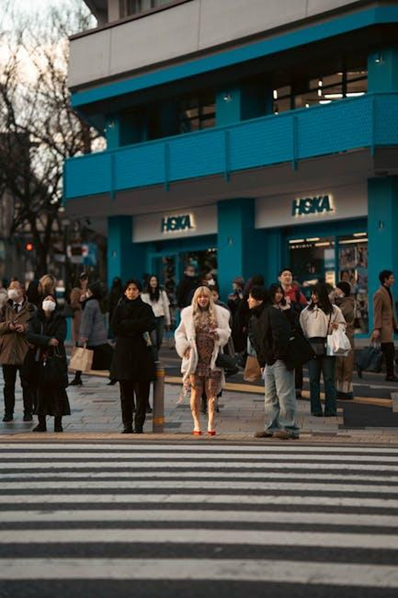 HOKA_Kawana_2_95_prezzo_originale_140_hpcmpJAcI4 - Confidenze24 Source: Viridiana Rivera - pexels - A bustling crosswalk in Tokyo with people waiting, featuring vibrant storefronts.