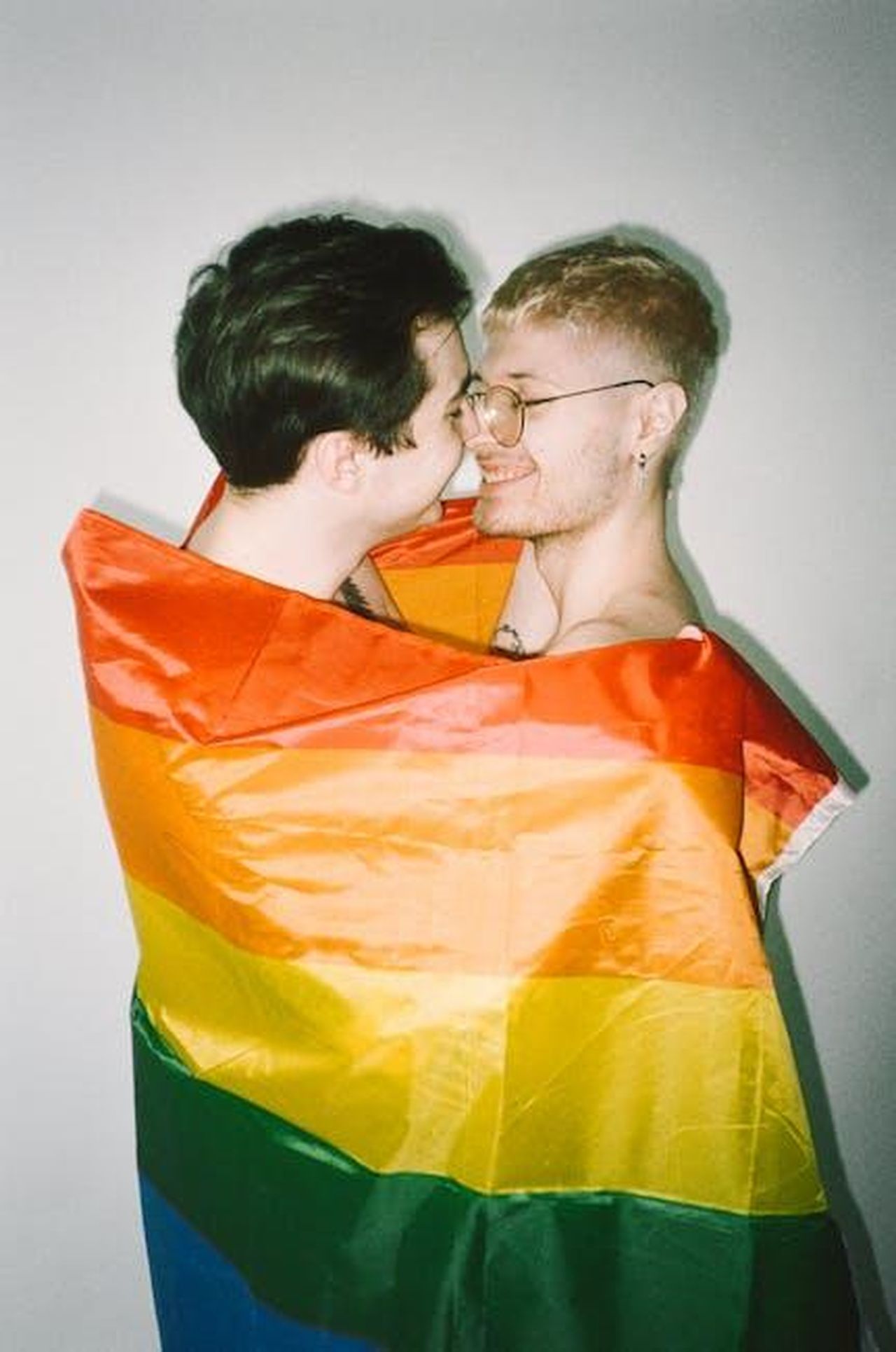 Ha_contribuito_alla_colonna_sonora_di_un_film_vincitore_di_un_Oscar_Yp2Nmr5B32 - Confidenze24 Source: Polina Tankilevitch - pexels - Happy LGBTQ couple wrapped in a vibrant pride flag, sharing a loving moment.