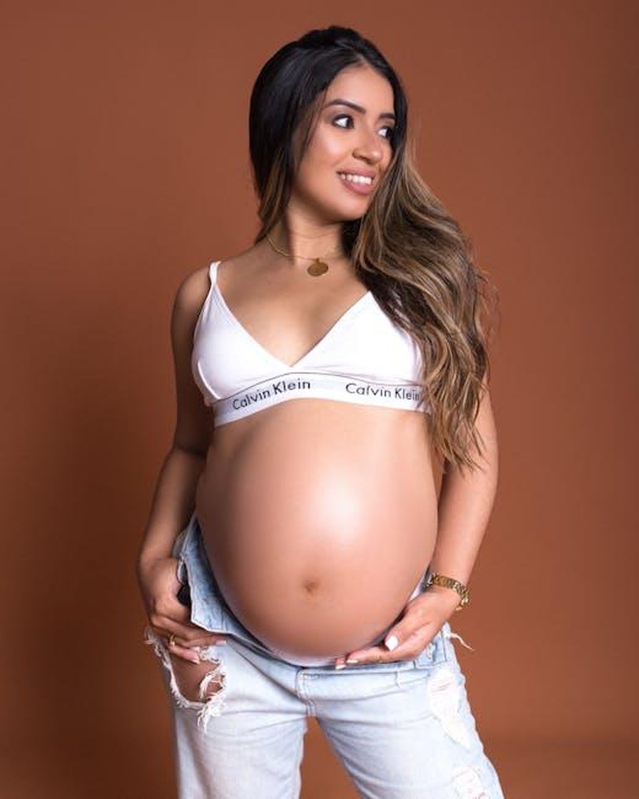 Ha_un_marchio_di_maternit_Rfa5HzMx0e - Confidenze24 Source: Marlon Schmeiski - pexels - Beautiful smiling pregnant woman in jeans and white top on brown background.