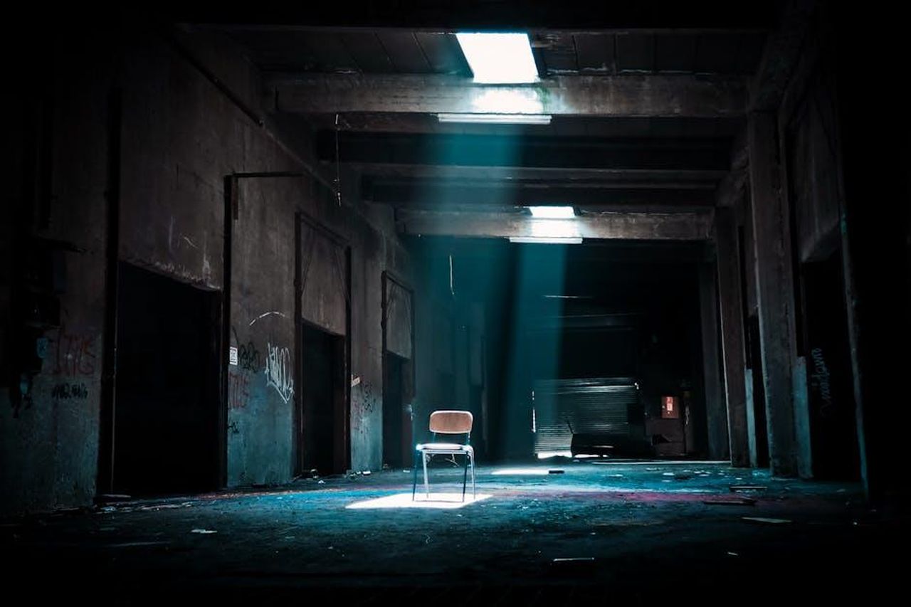Harry_come_spare_nella_vita_lavorativa_di_Meghan_XrXTN7Fqzr - Confidenze24 Source: Pixabay - pexels - Eerie abandoned warehouse with a solitary chair illuminated by sunlight, evoking mystery.