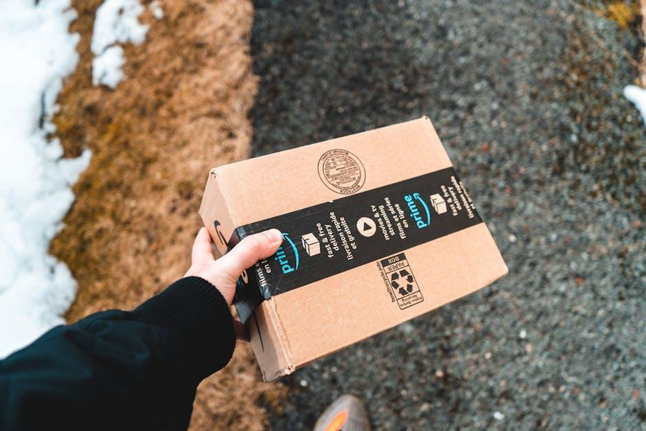Ho_bisogno_di_un_abbonamento_Amazon_Prime_per_partecipare_al_Big_Spring_Sale_P8tkh9Hijb - Confidenze24 Source: Erik Mclean - pexels - A person holding a cardboard Amazon Prime package on a snowy urban sidewalk.