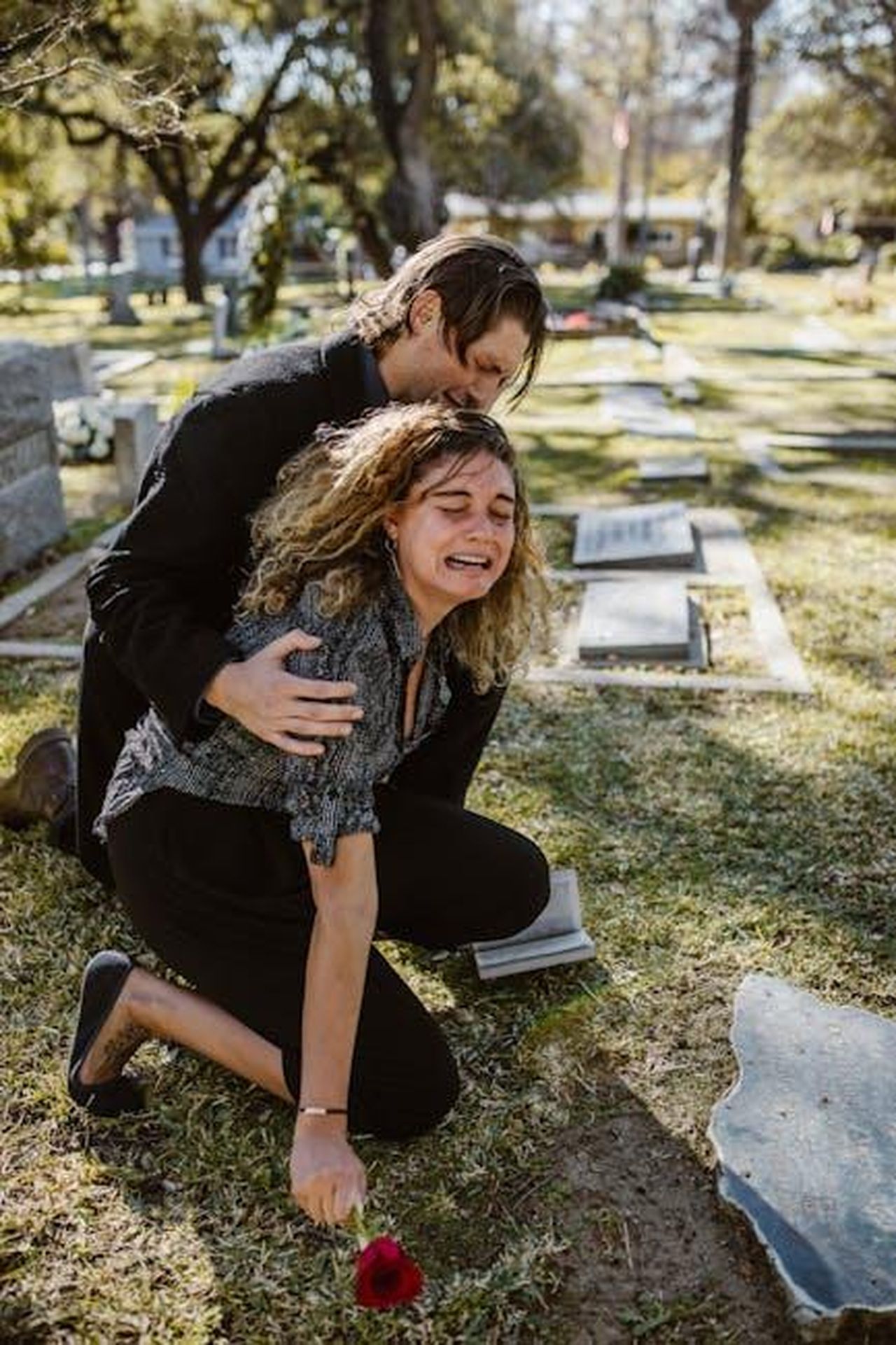 Ho_vissuto_la_stessa_cosa_sJYshmqvMl - Confidenze24 Source: RDNE Stock project - pexels - A poignant moment of grief in a sunlit cemetery with a couple mourning at a grave.