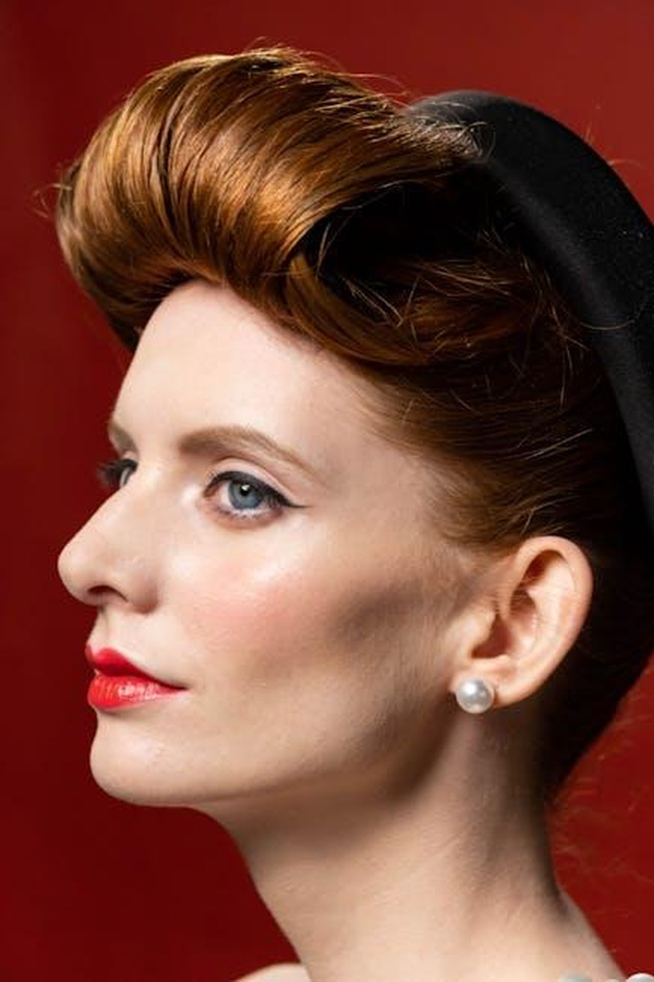 Hollywood_Icon_Alert_CToRqvMSm9 - Confidenze24 Source: cottonbro studio - pexels - Elegant portrait of a woman with retro hairstyle and pearls, set against a red background.