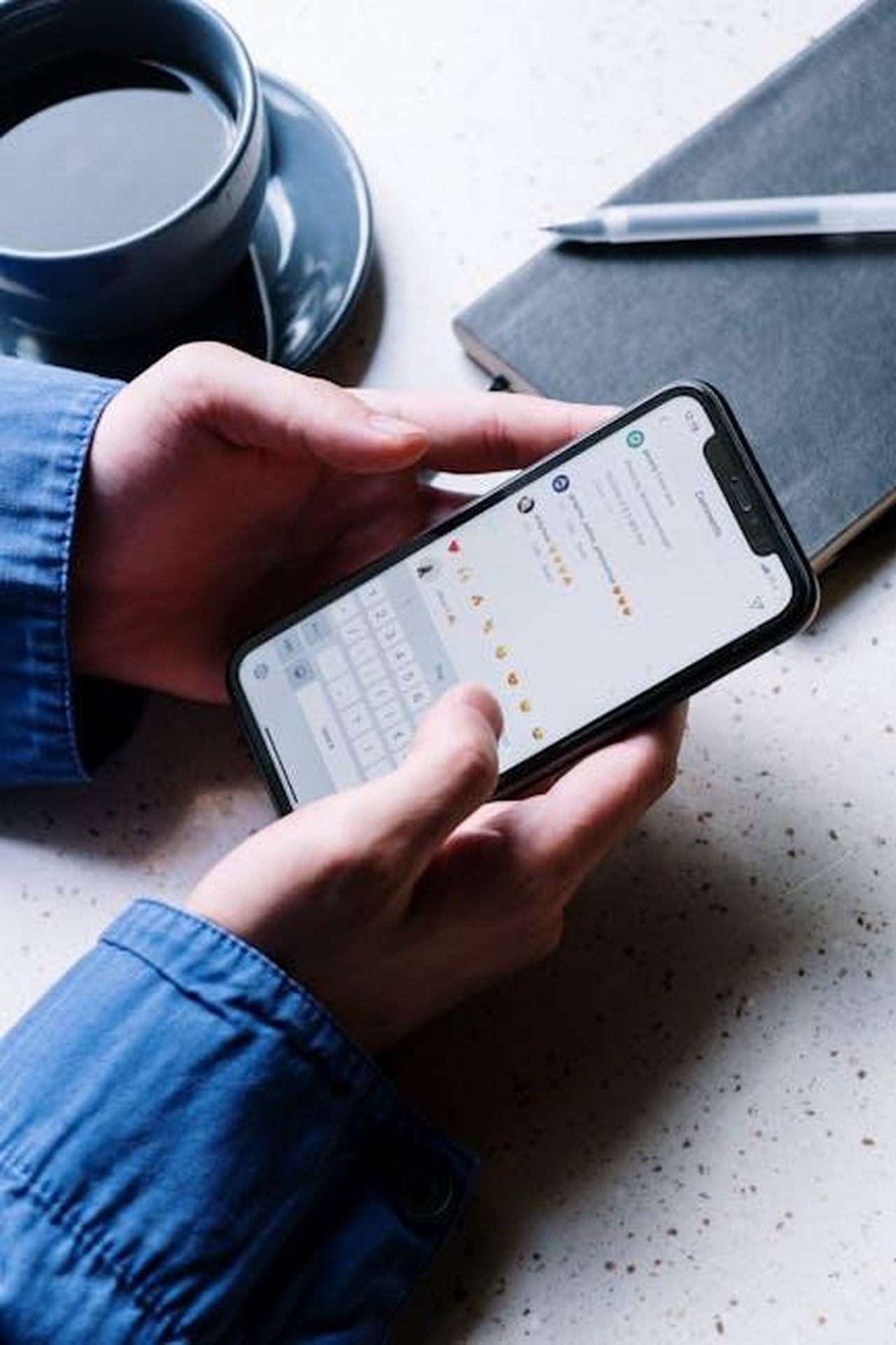 I_commenti_flirtanti_di_Jessica_su_Instagram_6Fj1eQph34 - Confidenze24 Source: cottonbro studio - pexels - Close-up of hands holding smartphone, using chat app. Coffee and notebook nearby indicate casual setting.