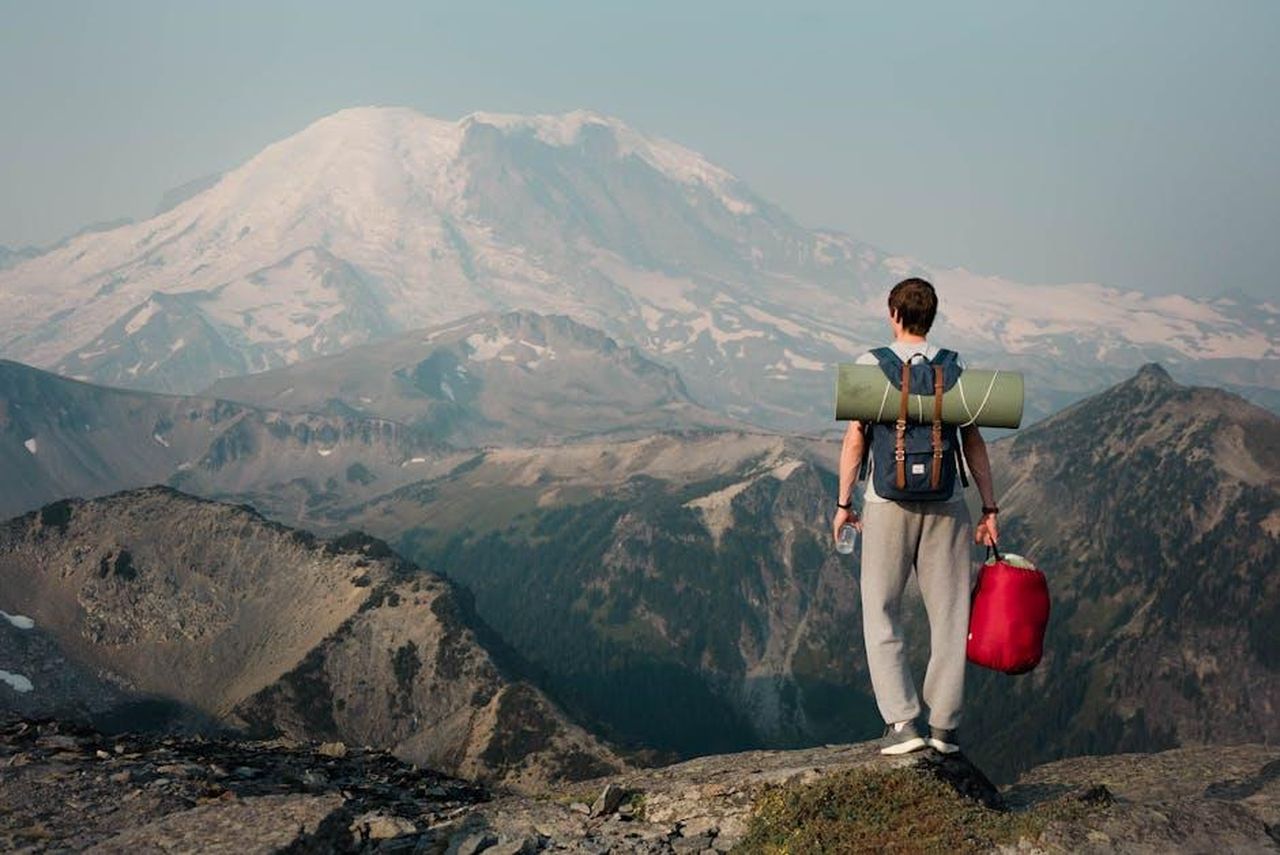 I_corpi_di_Gene_e_Betsy_YkCQwbQqEe - Confidenze24 Source: Dziana Hasanbekava - pexels - Backpacker on a mountain ridge gazing at a snow-covered peak, embracing adventure.
