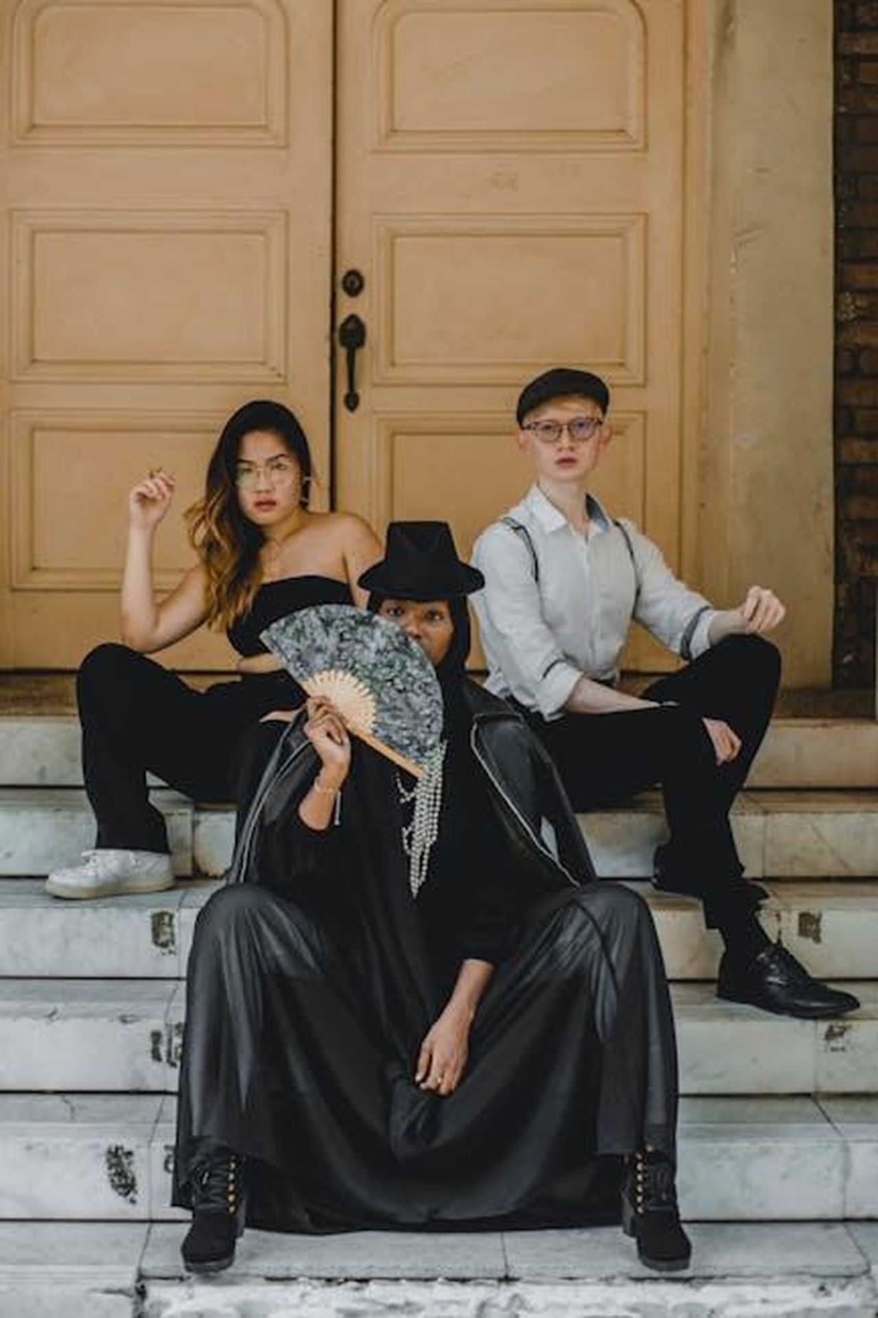 I_fan_di_Coronation_Street_sconcertati_dalle_scene_orribili_di_Cassie_RGXKZkLHmU - Confidenze24 Source: Cxpturing Souls - pexels - Three fashionable individuals in unique outfits pose on steps, exuding style and confidence.