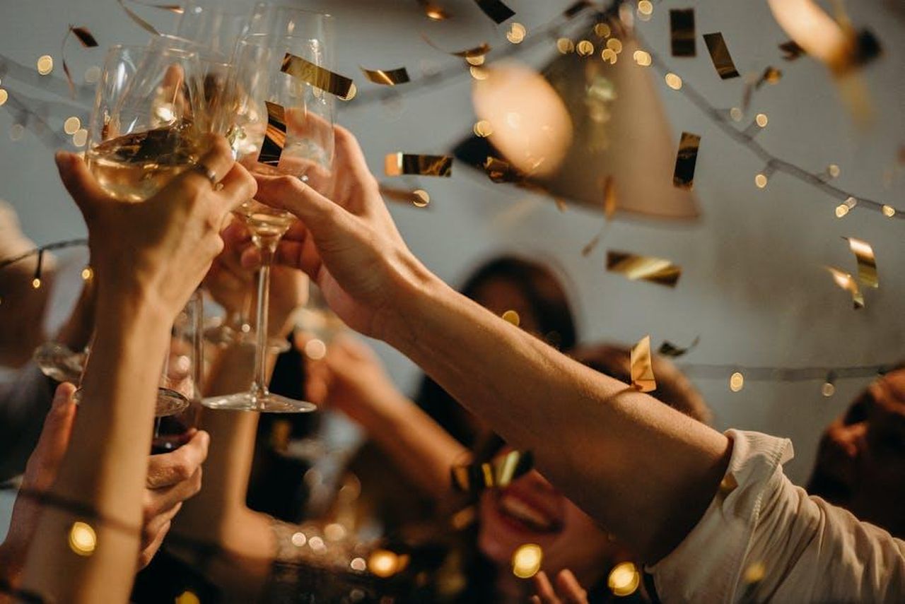 I_fan_di_Michelle_si_sono_lasciati_andare_a_complimenti_46PDqPO3oI - Confidenze24 Source: cottonbro studio - pexels - A lively indoor party scene with people toasting champagne glasses amid confetti and warm lights.