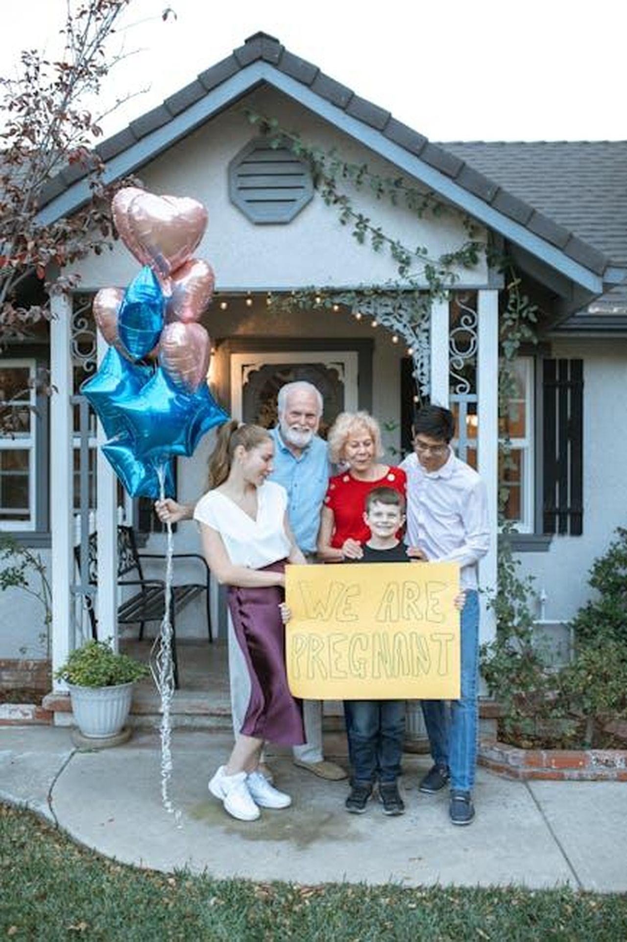 I_fan_esultano_per_la_notizia_della_nascita_della_bambina_di_Michelle_e_Mark_XRLaf3aNgi - Confidenze24 Source: RDNE Stock project - pexels - A family joyfully announces a pregnancy with a sign and balloons outside their home.