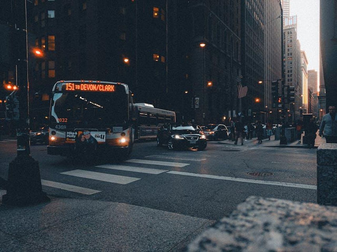 I_fan_esultano_per_la_notizia_di_Rylan_5QHRUGANLX - Confidenze24 Source: Allen Boguslavsky - pexels - A city bus navigates bustling urban streets at dusk, showcasing public transportation in action.
