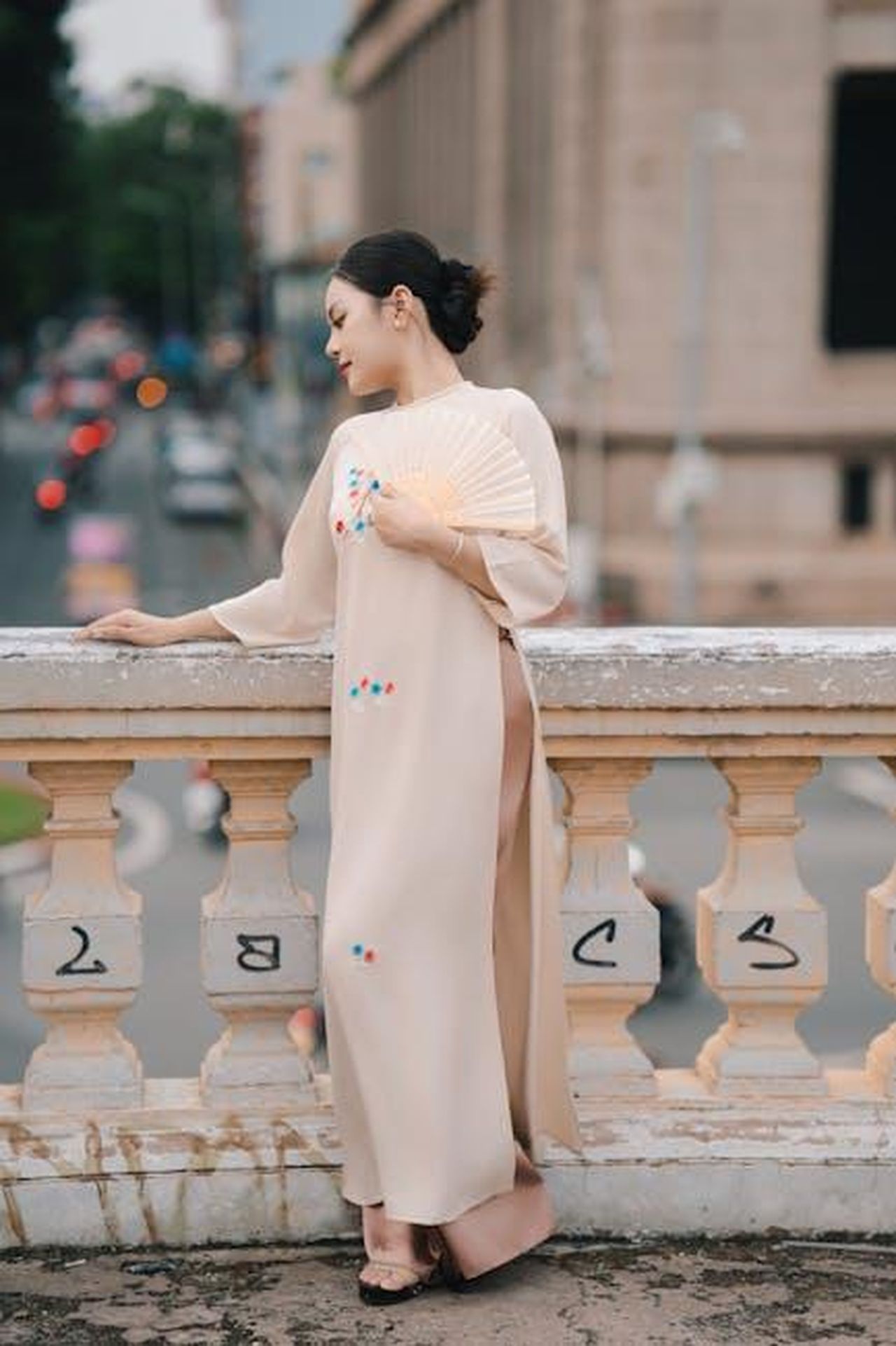 I_fan_si_interrogano_sullassenza_di_Bobby_in_Tracker_FYp9ddjljZ - Confidenze24 Source: nguyen kha - pexels - Woman in traditional attire holding a fan on an urban balcony.
