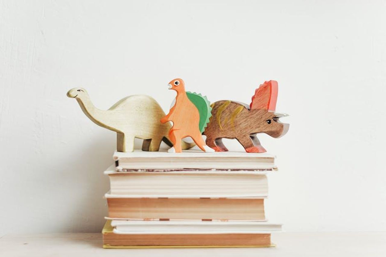 I_libri_che_hanno_influenzato_Meghan_iBR1rvMJBb - Confidenze24 Source: cottonbro studio - pexels - Colorful wooden dinosaurs on top of a stack of hardcover books on a light background.