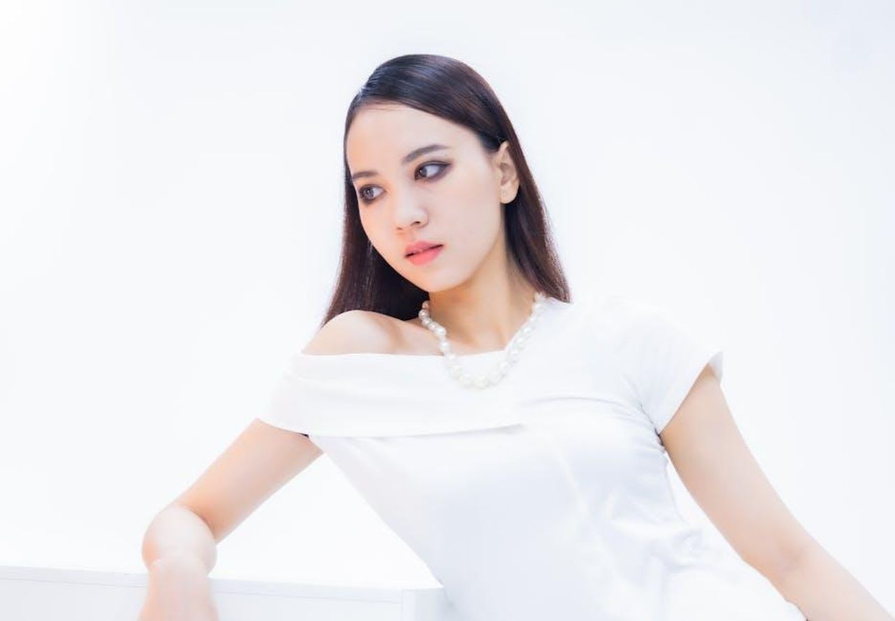 I_pezzi_pi_popolari_della_collezione_fNQepTkyn3 - Confidenze24 Source: Quý Nguyễn - pexels - Portrait of a woman in a white dress with a pearl necklace against a bright background.