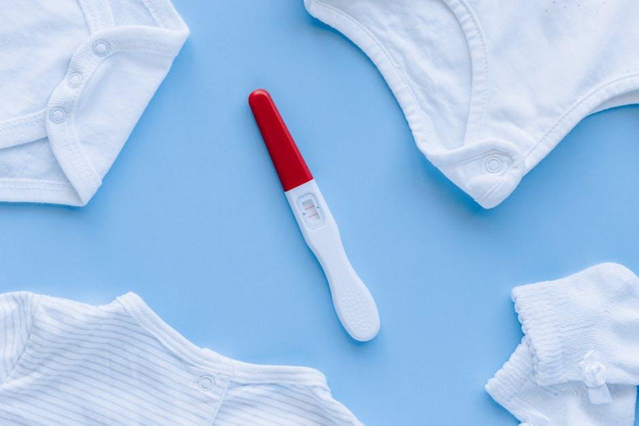 I_risultati_hanno_chiarito_la_questione_AHH6JhKVM2 - Confidenze24 Source: Nataliya Vaitkevich - pexels - Flat lay of positive pregnancy test surrounded by baby clothes on blue background.