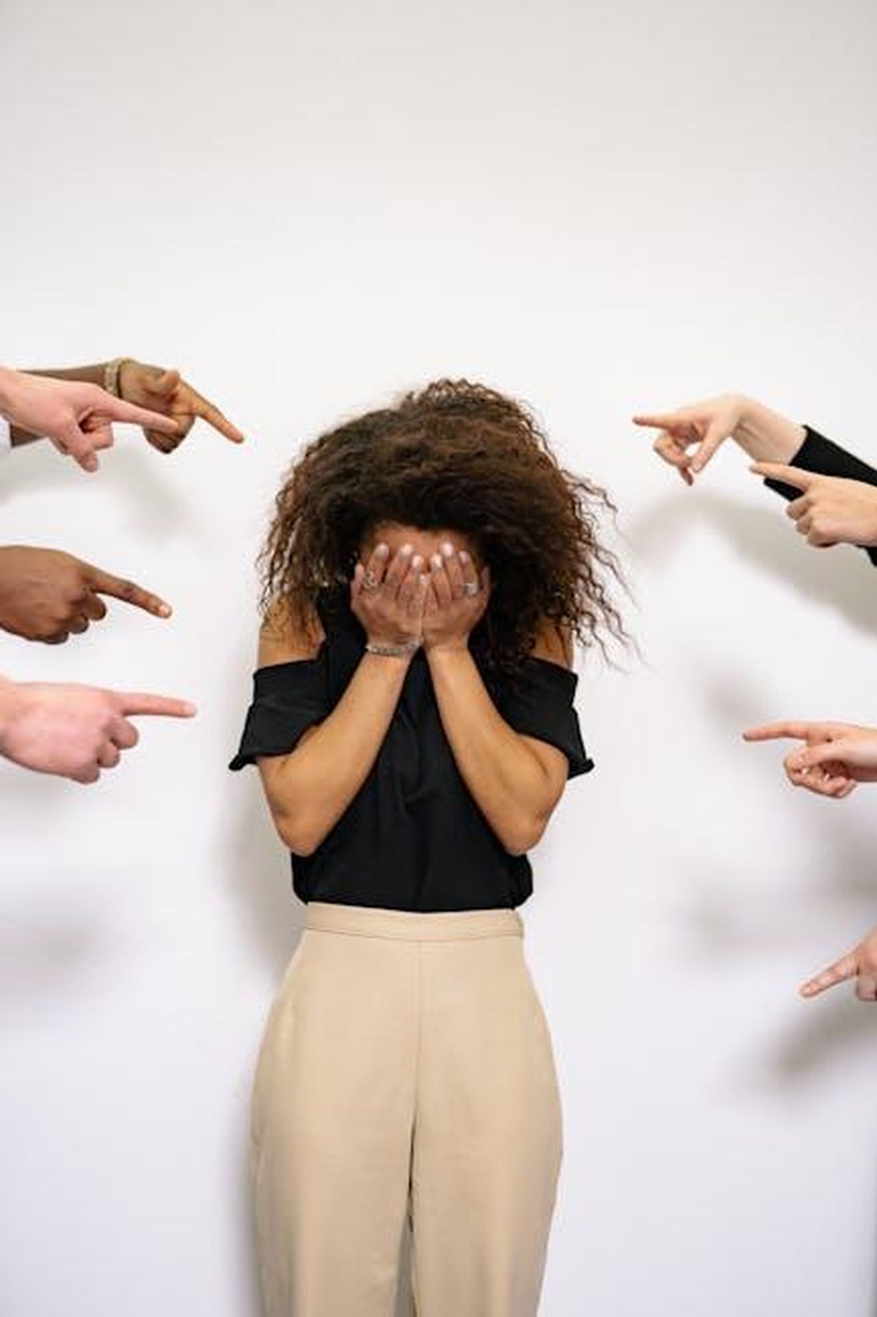 I_telespettatori_criticano_Ben_per_lintervista_non_professionale_z1YCbfnRDg - Confidenze24 Source: Yan Krukau - pexels - A stressed woman covers her face as multiple hands point accusatorily in a studio setting.