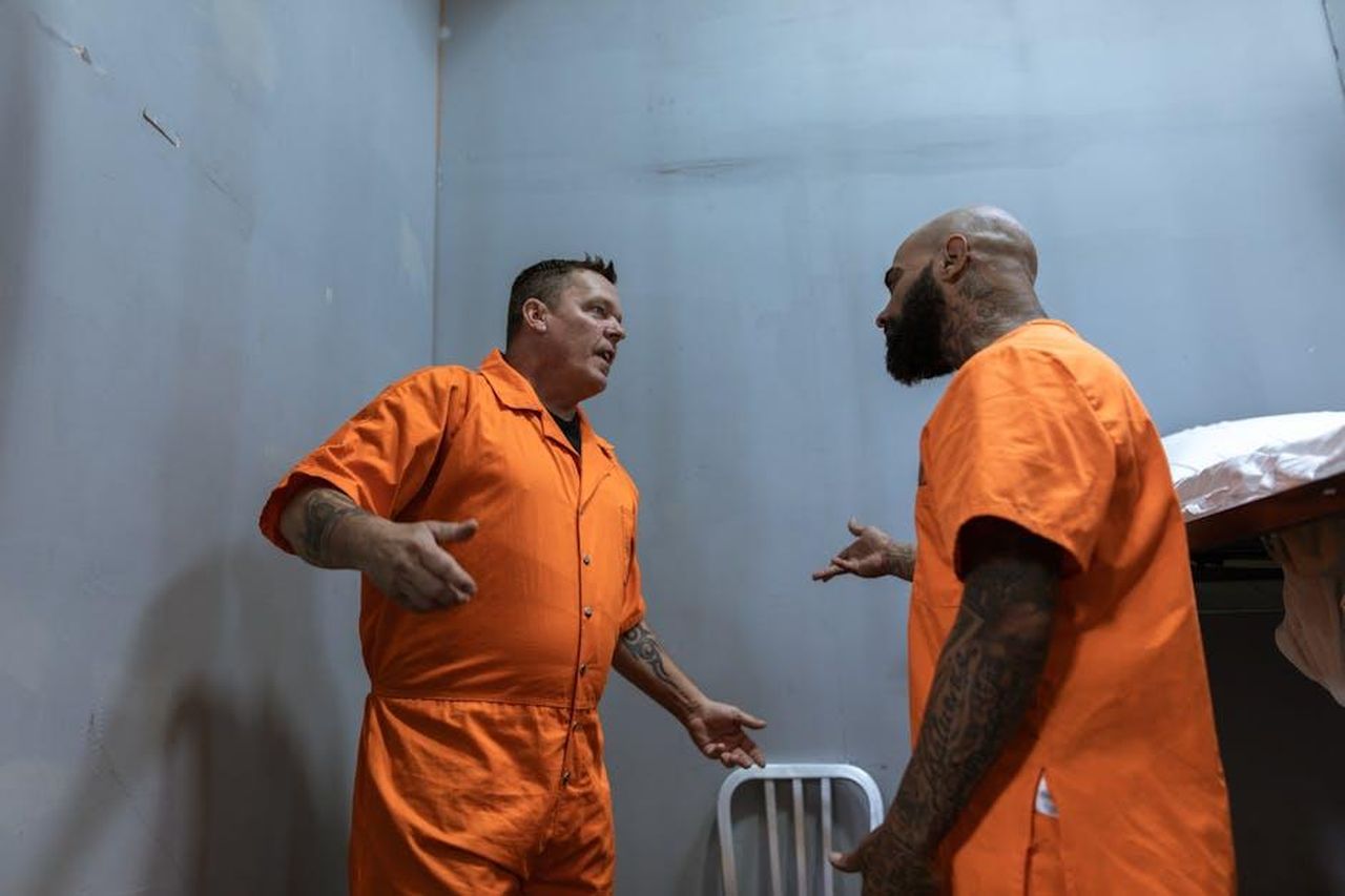 Il_dialogo_tra_Billie_e_Reenie_in_prigione_ML4KaAMbhR - Confidenze24 Source: RDNE Stock project - pexels - Two male prisoners in orange jumpsuits talking inside a prison cell.