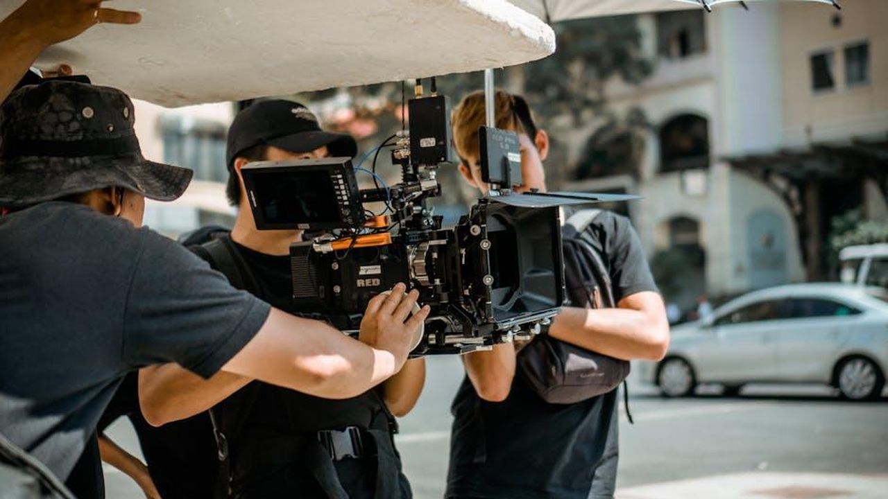 Il_direttore_Michael_Steed_elogia_Meghan_come_boss_e2V2oEstV4 - Confidenze24 Source: Lê Minh - pexels - A film crew operates a RED camera on a city street, capturing a professional scene.