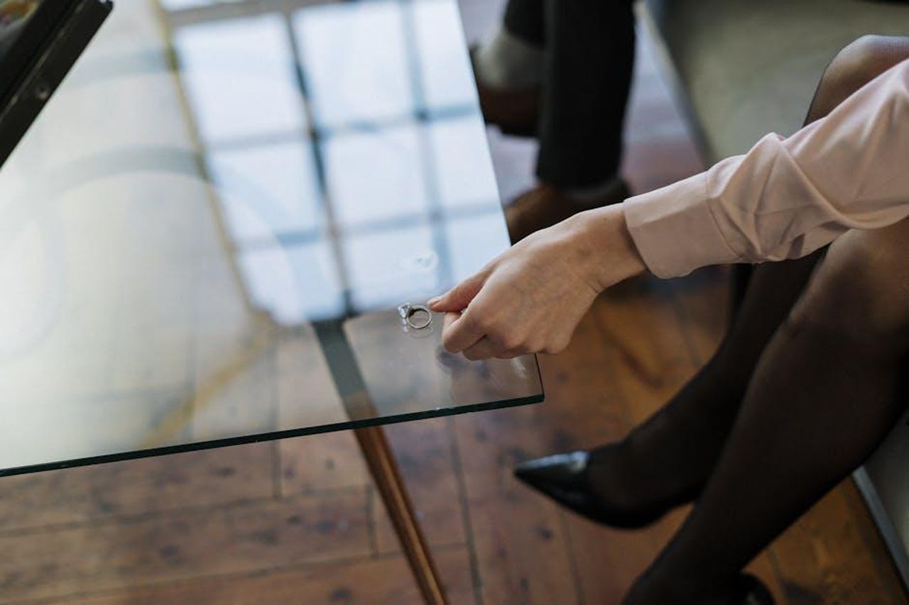 Il_divorzio_di_Jessica_Alba_un_nuovo_inizio_5yrxvx8LeP - Confidenze24 Source: cottonbro studio - pexels - Close-up of a woman placing a wedding ring on a glass table, symbolizing relationship changes.