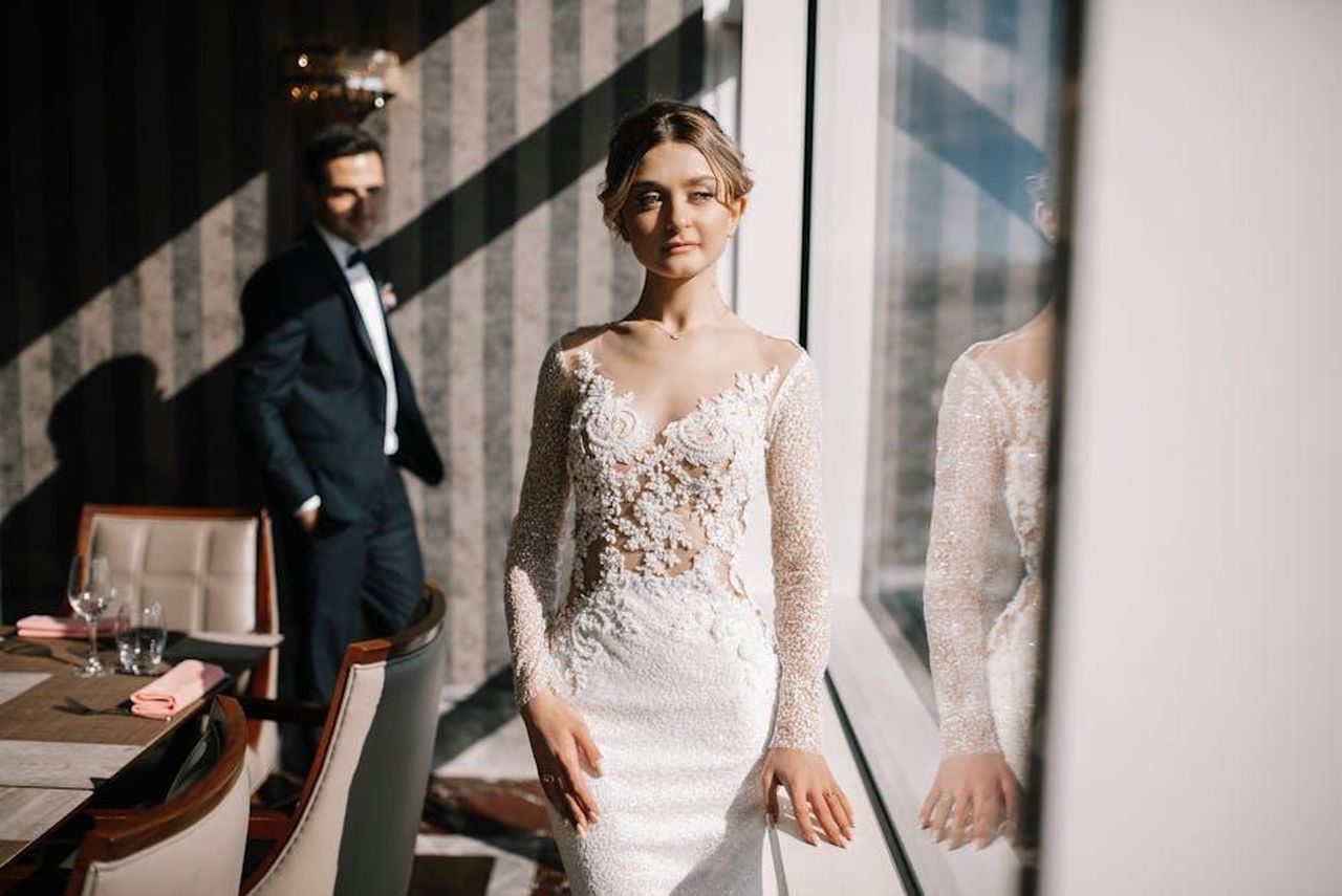 Il_giorno_del_matrimonio_di_Georgia_Toffolo_yXrqEZ4Lu6 - Confidenze24 Source: Nika Zhorzholiani - pexels - Romantic indoor wedding photoshoot displaying the bride in an elegant gown with groom in background.