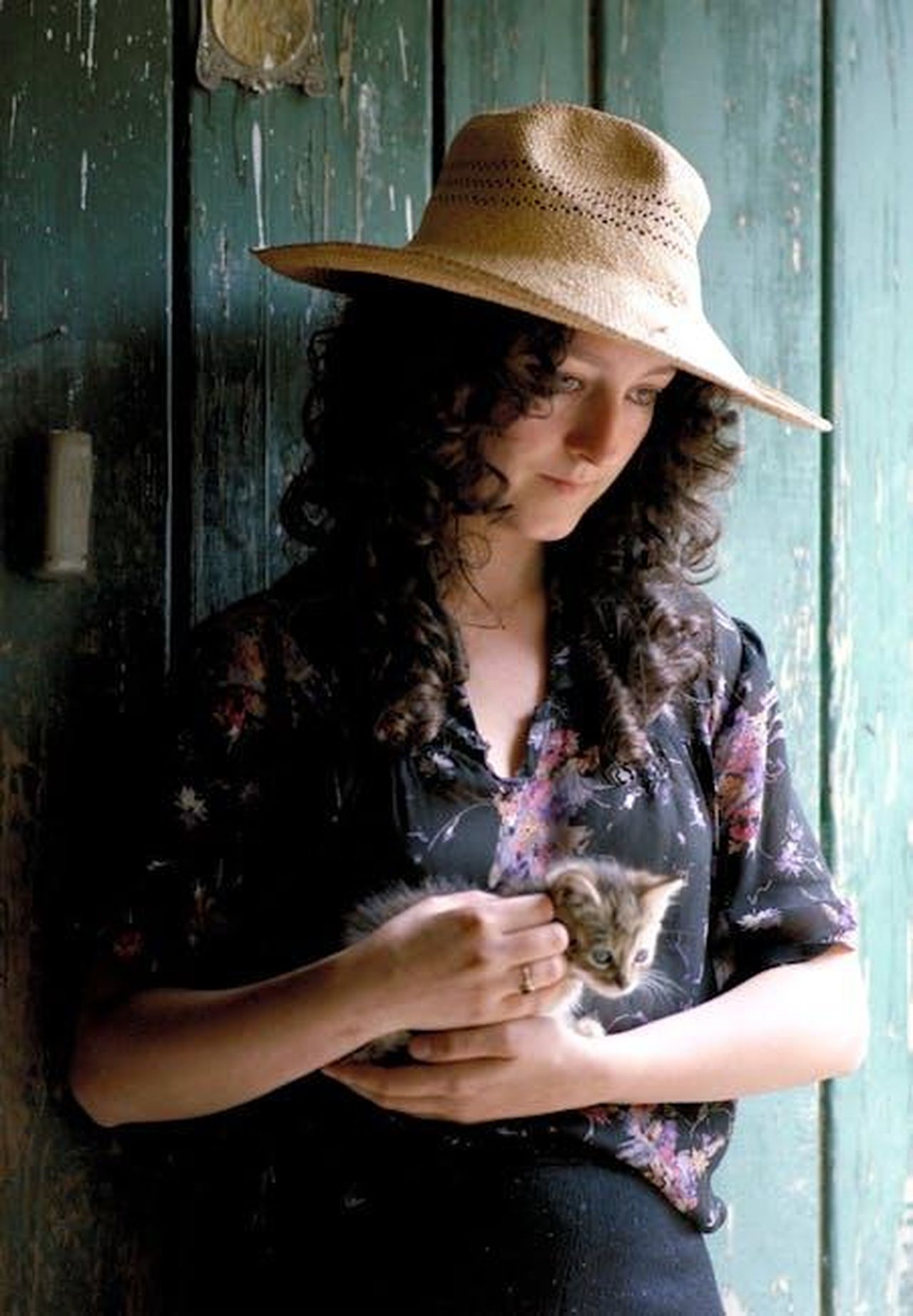 Il_guardaroba_di_Cat_XIHXv5e7Bz - Confidenze24 Source: José Antonio Otegui Auzmendi - pexels - A woman wearing a straw hat gently holds a small kitten in an indoor rustic setting.