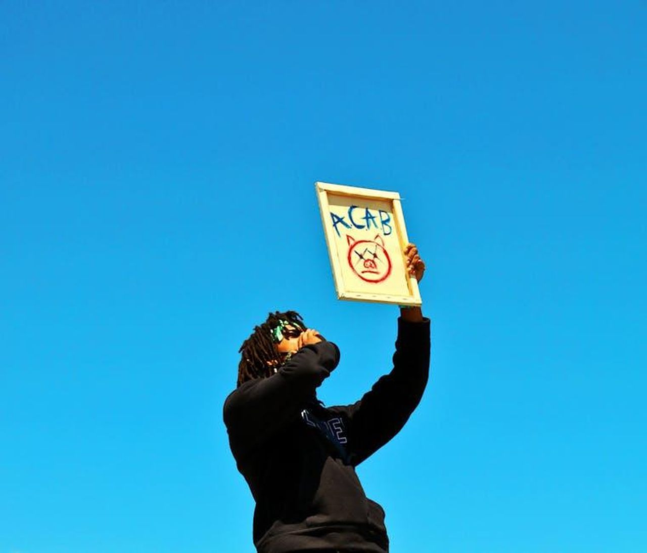 Il_legame_con_Donald_Trump_JDCPoyi4gP - Confidenze24 Source: Eric Yeich - pexels - A protester raises a sign during a demonstration in Los Angeles under a clear blue sky.