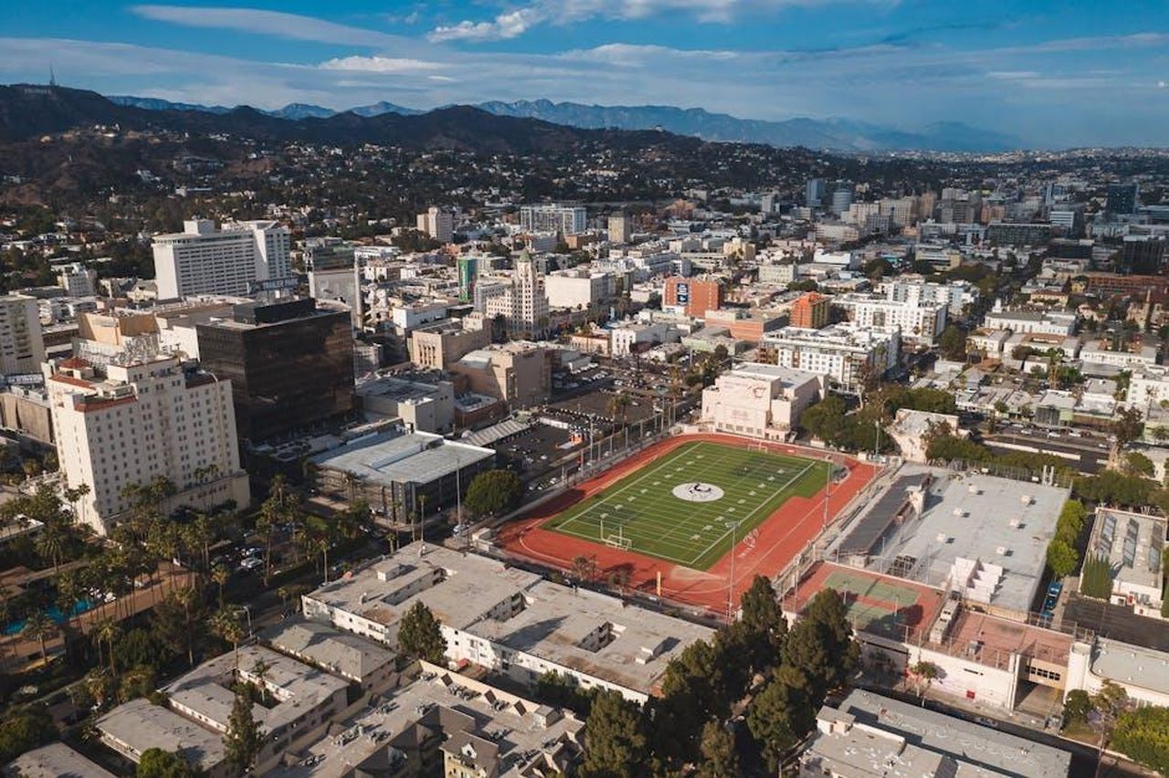 Il_legame_con_la_comunit_di_Hollywood_fpQtmHWi6j - Confidenze24 Source: RDNE Stock project - pexels - Stunning aerial view of Los Angeles cityscape featuring a prominent football field in the foreground.