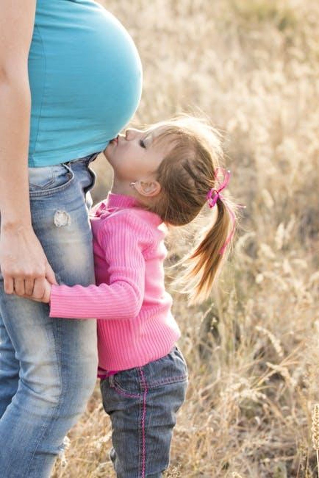 Il_legame_speciale_tra_madre_e_figli_maschi_5mWarSHZb6 - Confidenze24 Source: Pixabay - pexels - A young girl lovingly kisses her pregnant mother's belly outdoors, symbolizing family affection.