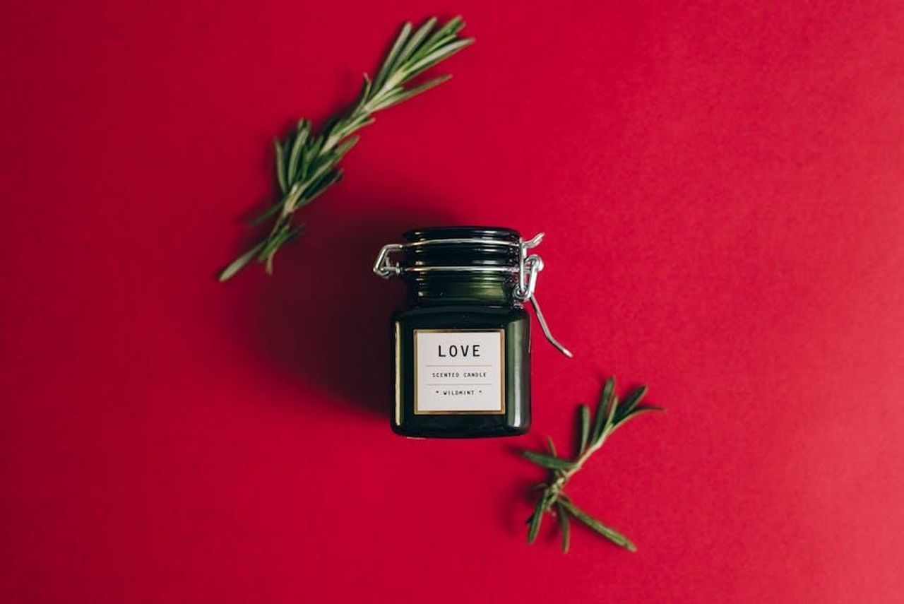 Il_marchio_tossico_di_Harry_ASoAq6T7K0 - Confidenze24 Source: Leeloo The First - pexels - Overhead shot of a black scented candle jar with sprigs on a red background.