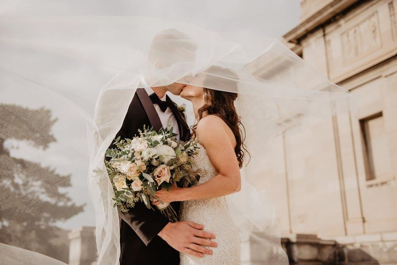 Il_matrimonio_di_Taylor_e_Daniel_W2hxPTkXgl - Confidenze24 Source: Emma Bauso - pexels - Bride and groom share a tender kiss under a veil, showcasing love and romance on their special day.