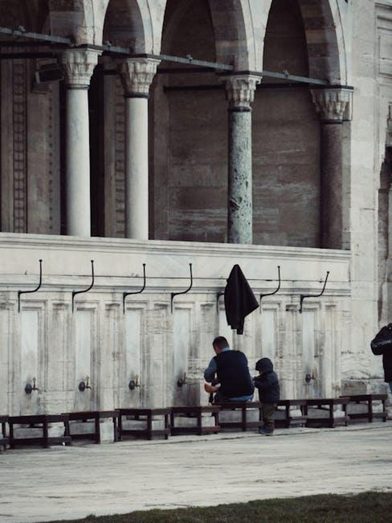 Il_messaggio_di_Beckham_per_le_sue_figlie_GQIvKU19ZC - Confidenze24 Source: Şeyma D. - pexels - A man and a child performing ablution at an outdoor mosque fountain with historic arches.