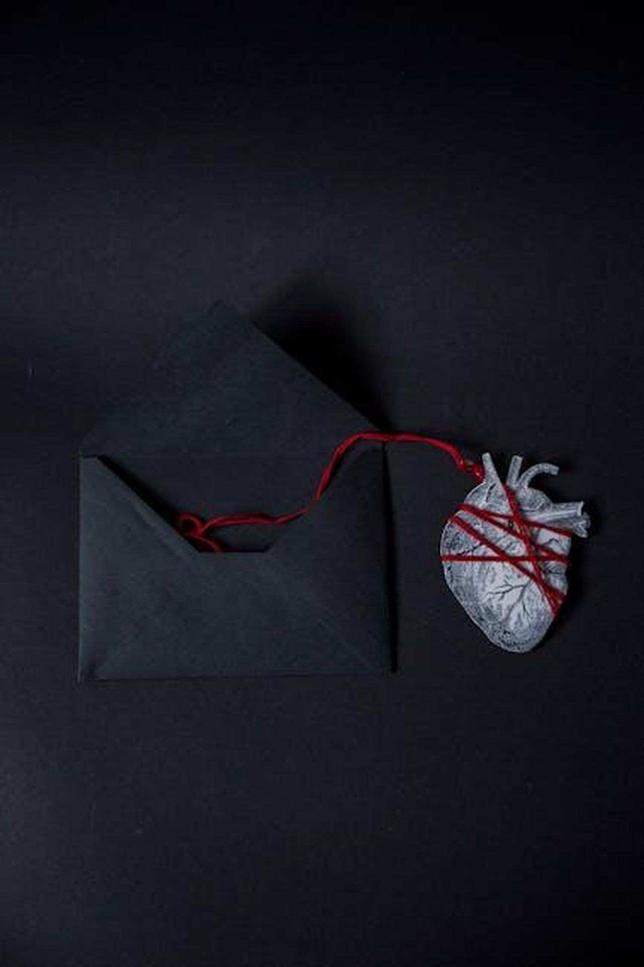 Il_mistero_della_foto_di_Capodanno_con_Jonathan_Davino_dQMY0I4tDA - Confidenze24 Source: Olga Lazacovici - pexels - Conceptual black envelope and heart with red string on black background, showcasing creativity and emotion.