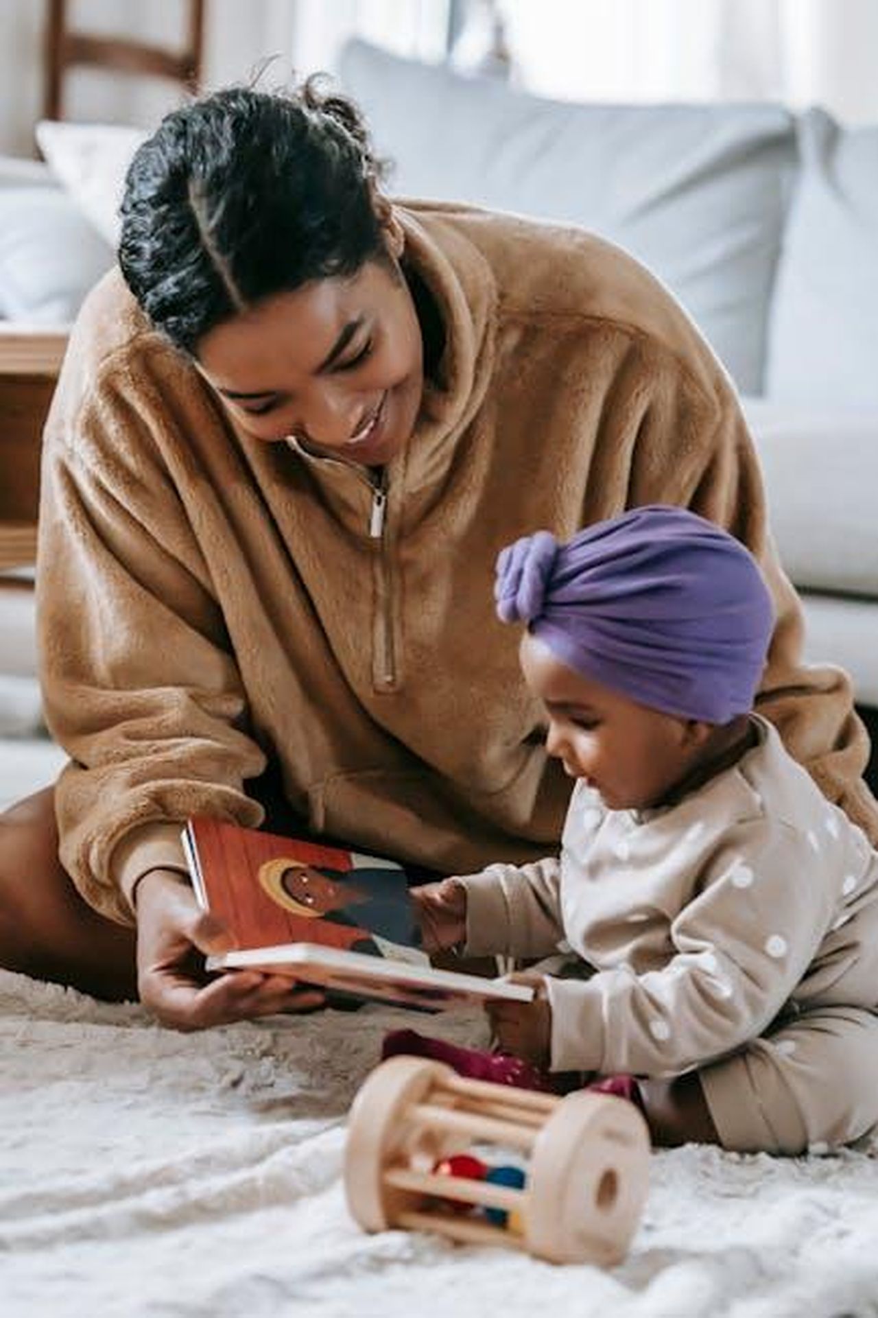 Source: William Fortunato - pexels - A mother and her baby enjoying a bonding moment while reading indoors.