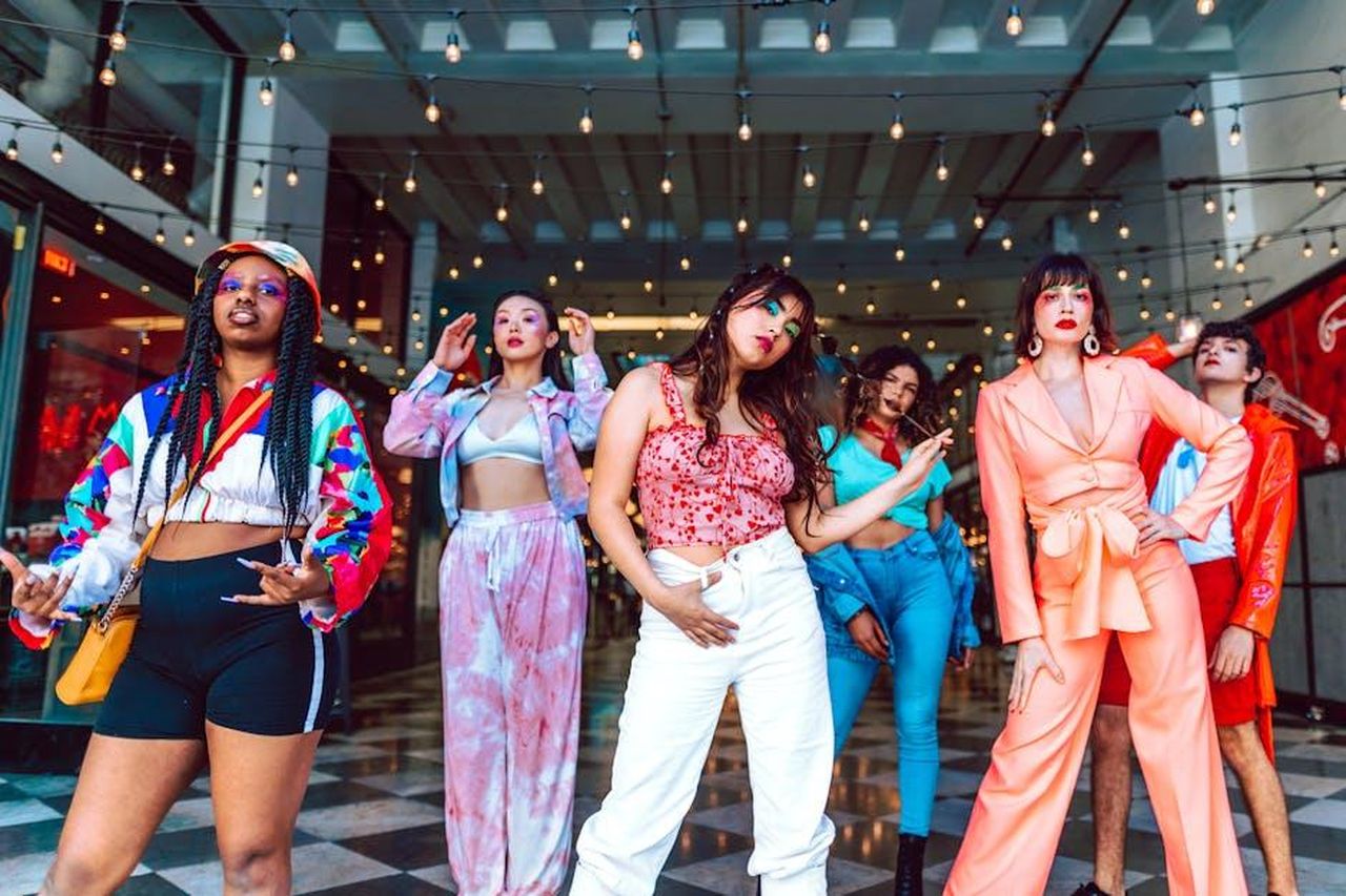 Il_passato_della_girl_squad_di_Taylor_Swift_bOVhxgJsmi - Confidenze24 Source: RDNE Stock project - pexels - A diverse group of stylish young adults posing confidently under string lights indoors.