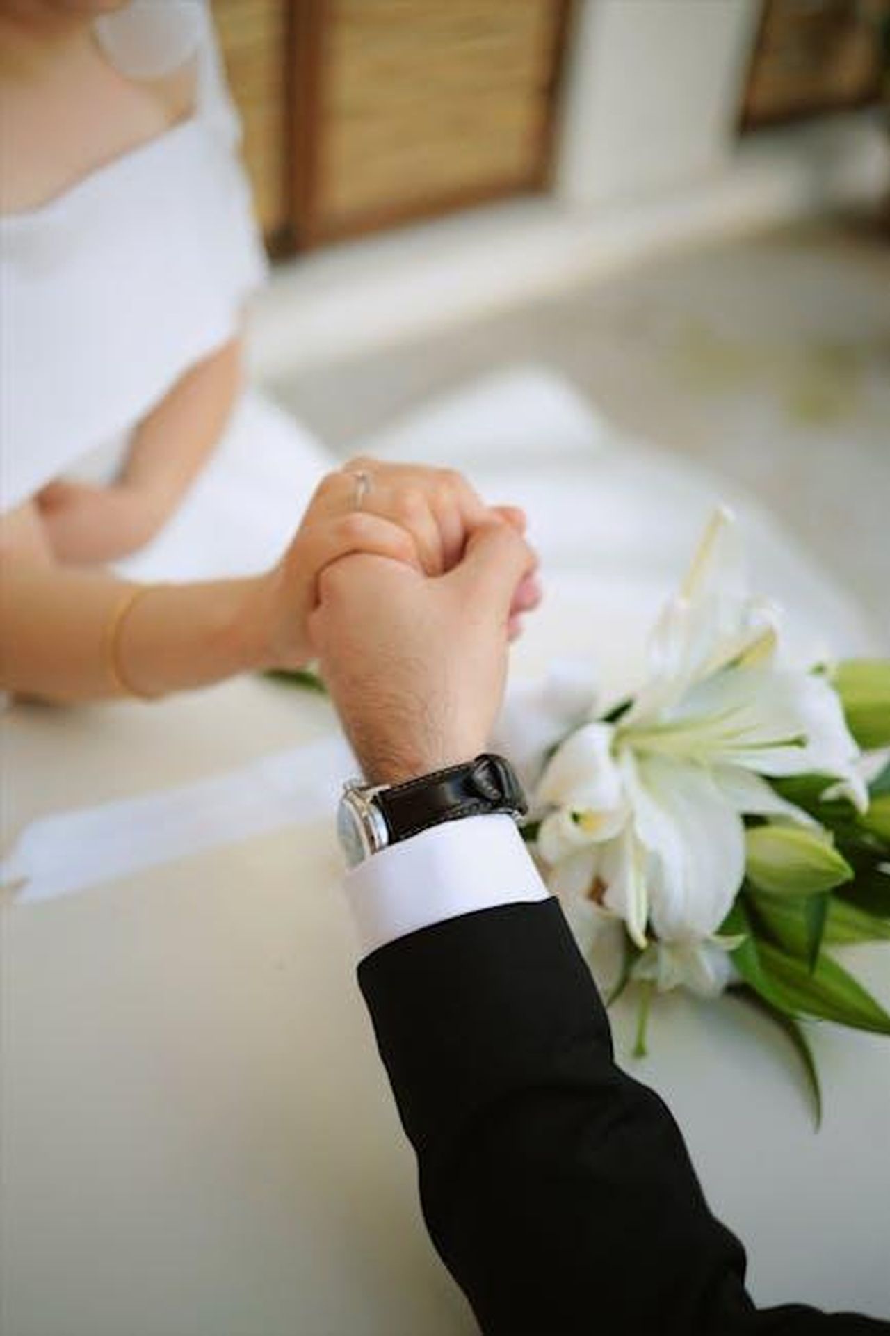Il_passato_di_Justin_Theroux_con_Jennifer_Aniston_rVLLcVSDgY - Confidenze24 Source: esrannuur - pexels - Close-up of a couple holding hands at a wedding ceremony with white lilies.