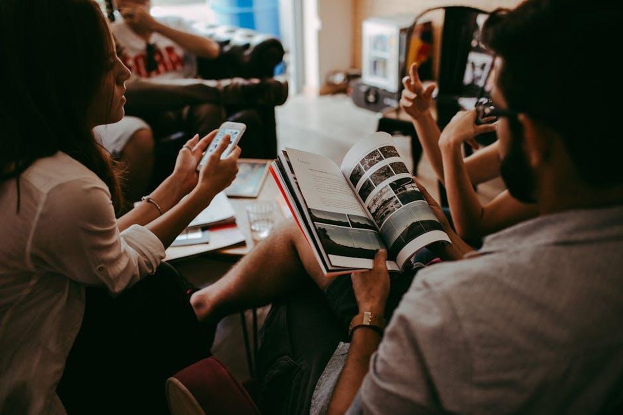 Il_potere_di_un_libro_condiviso_zi6184a8yM - Confidenze24 Source: Helena Lopes - pexels - Casual group discussion with people reading a magazine and interacting indoors.