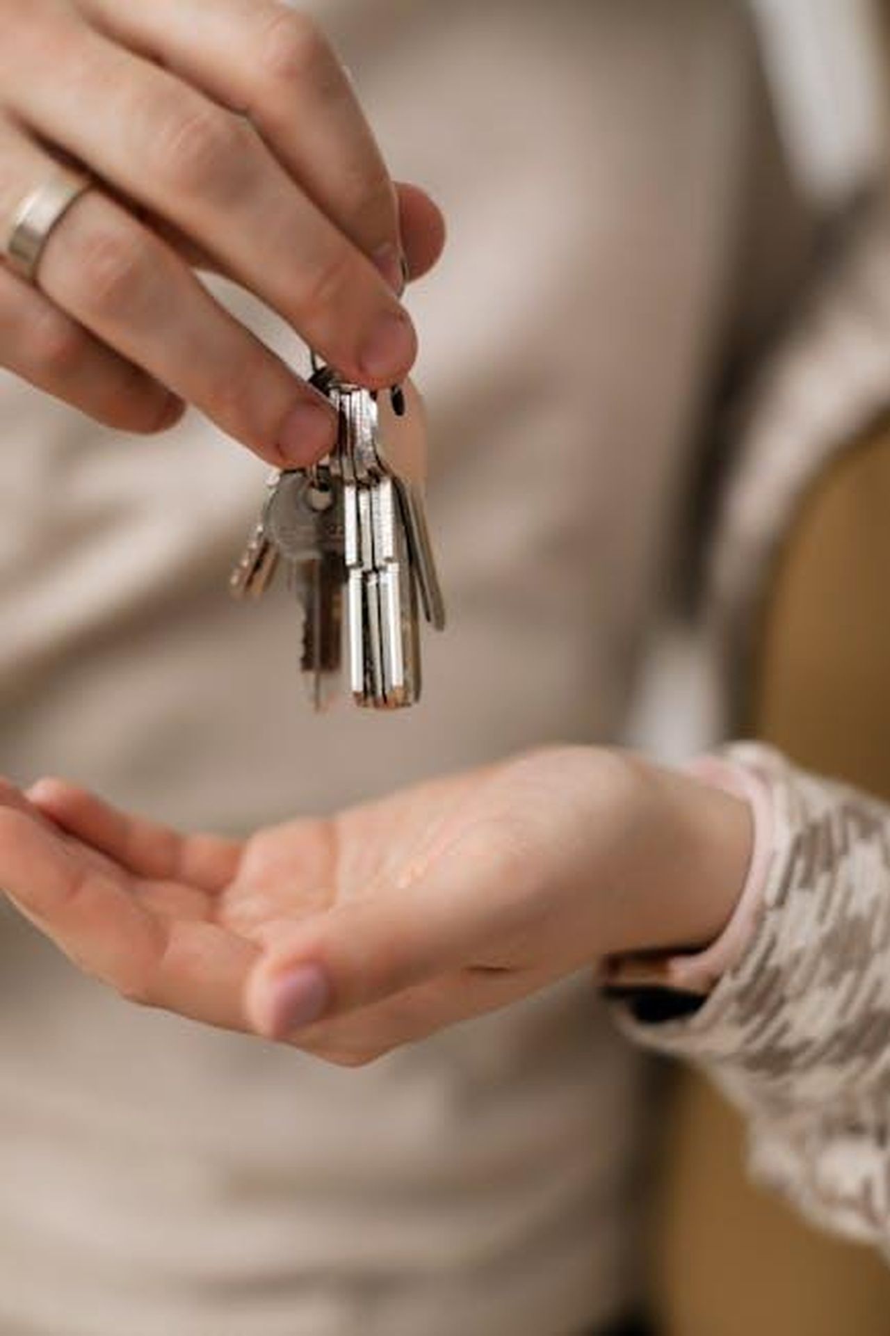 Il_primogenito_come_uomo_di_casa_Zm3jFr3gGD - Confidenze24 Source: Alena Darmel - pexels - A close-up photograph of hands exchanging keys, symbolizing new home ownership.