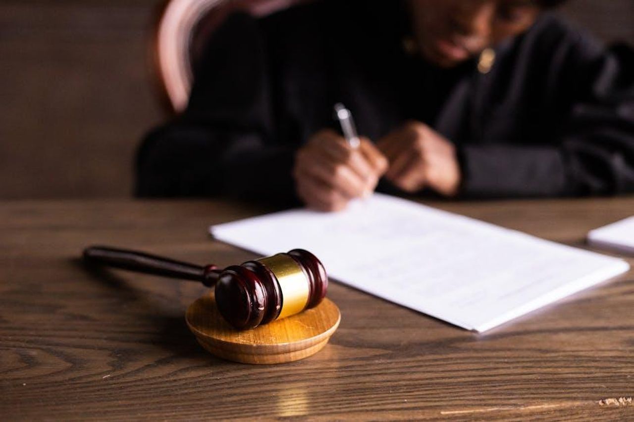 Il_processo_di_Jonathan_Majors_condanna_per_aggressione_ws4LKfVCwu - Confidenze24 Source: KATRIN BOLOVTSOVA - pexels - Judge signing documents at desk with focus on gavel, representing law and justice.