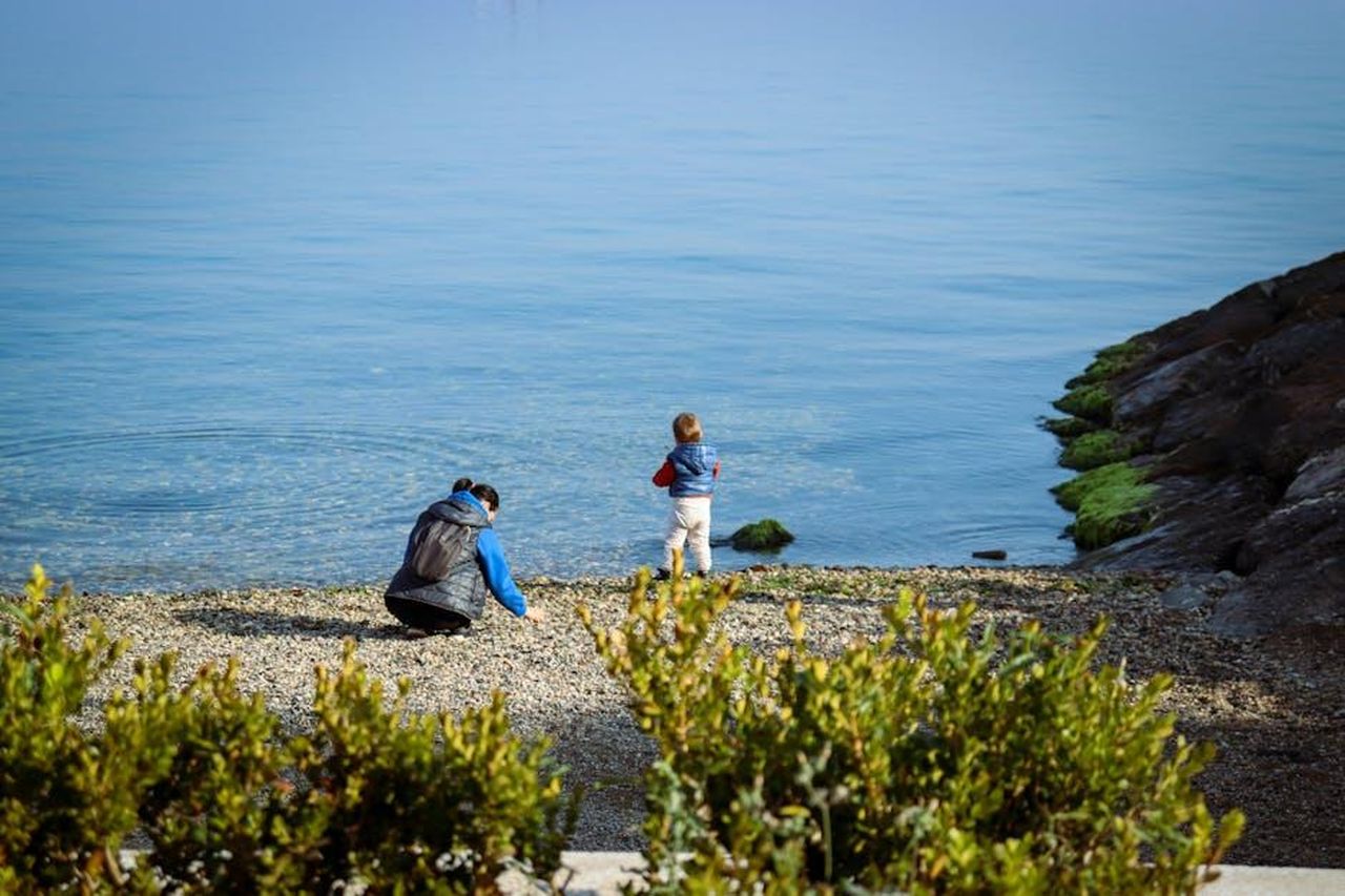 Il_rapporto_con_i_genitori_e_la_fede_jYHSotKvXM - Confidenze24 Source: Eda Karabulut - pexels - A parent and child enjoy a serene moment by the calm lakeside with clear water.