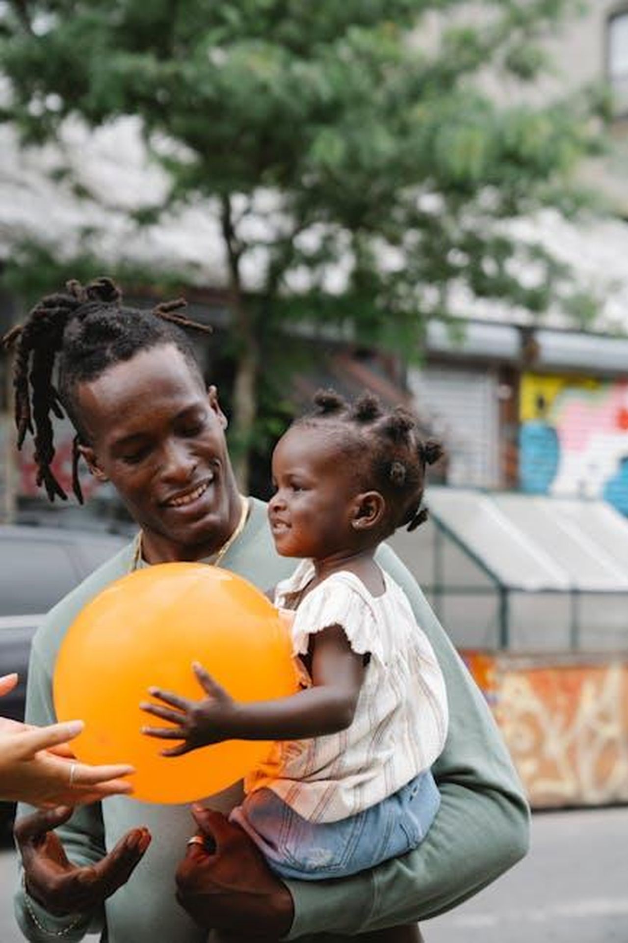 Il_rapporto_di_Vivian_con_i_genitori_E1kn1PDODX - Confidenze24 Source: Greta Hoffman - pexels - A father and daughter share a joyful moment outdoors with an orange balloon.