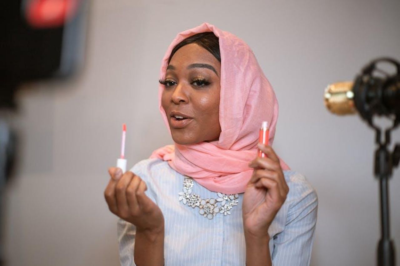 Il_ruolo_dello_stylist_di_Kelce_Tom_Marchitelli_HFN66FCvNc - Confidenze24 Source: RDNE Stock project - pexels - Muslim woman in a pink headscarf sharing beauty tips with lip gloss in a vlog setup.